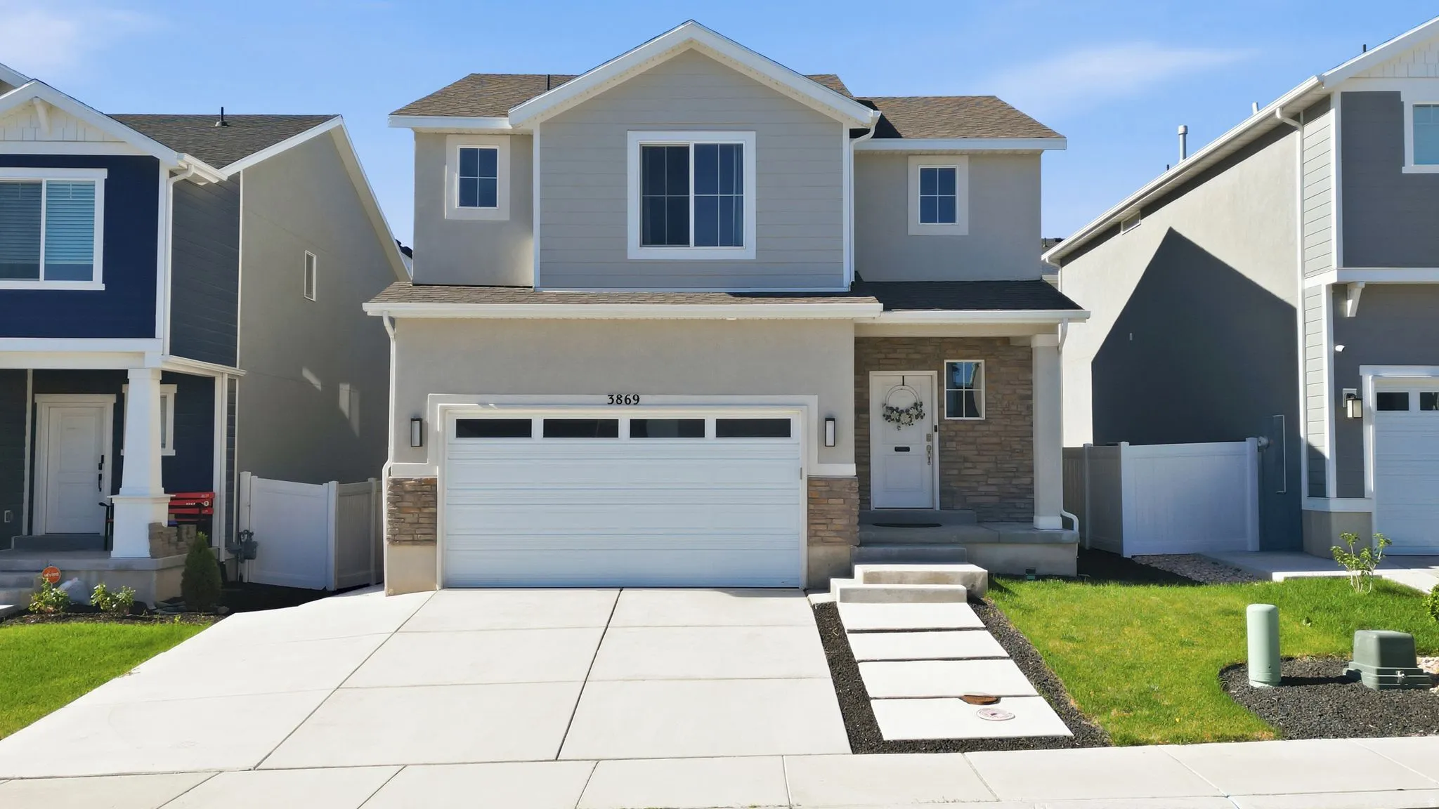 Two-story residence featuring a light gray exterior with stone accents and white trim