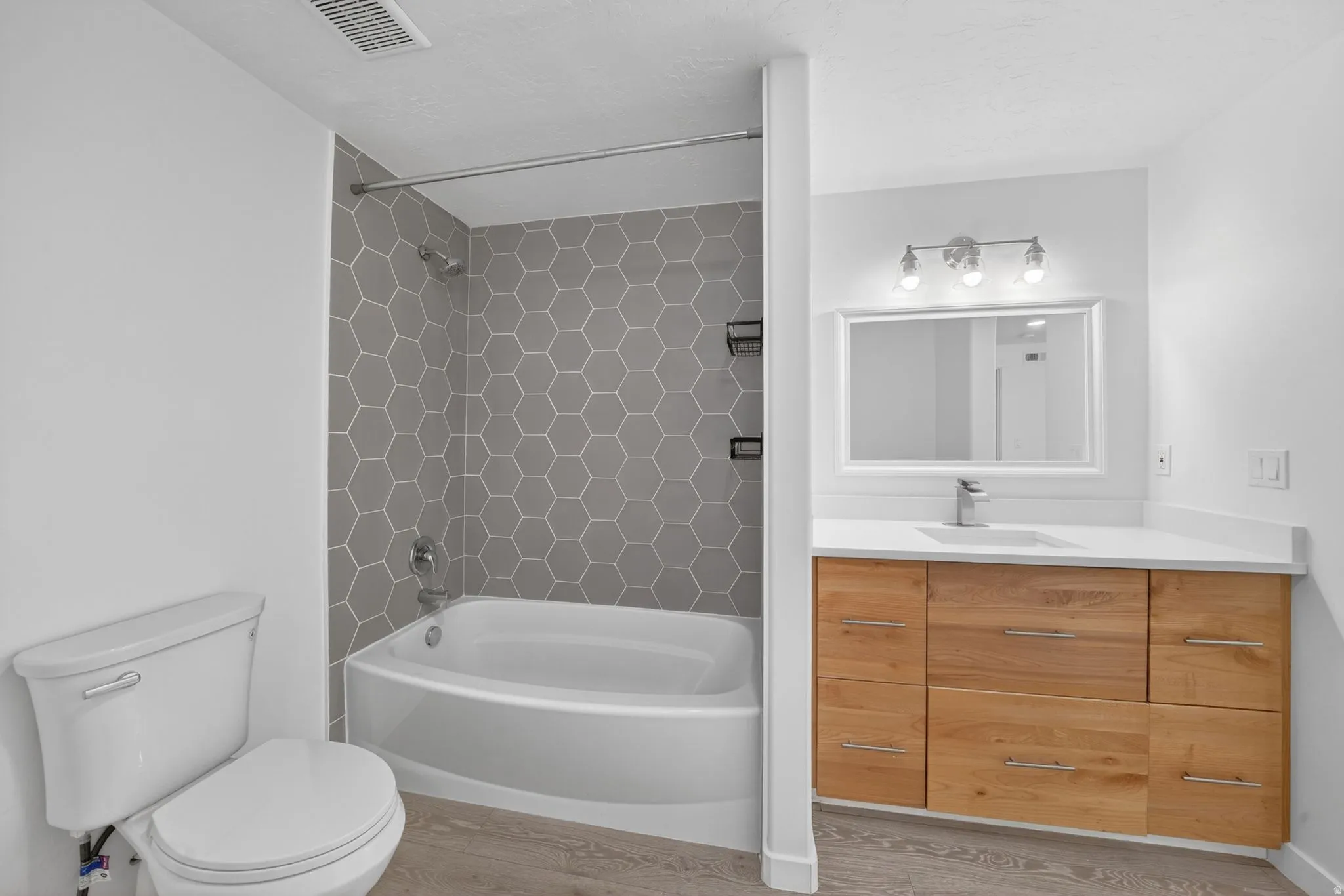 Bathroom featuring a wood-finish vanity with a white countertop, an undermount sink, and a framed mirror