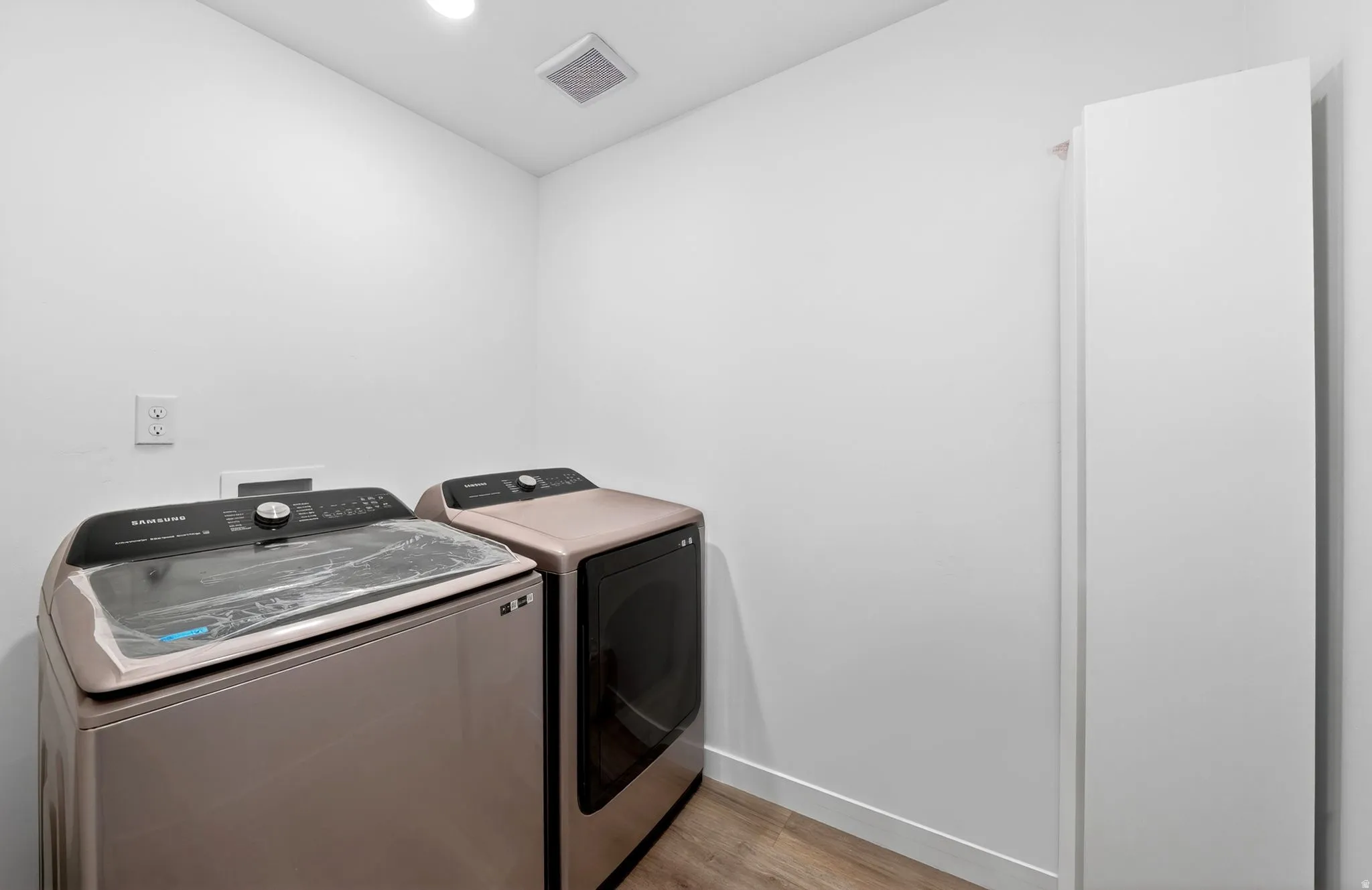 Dedicated laundry space featuring a white built-in storage cabinet and wood-finish flooring