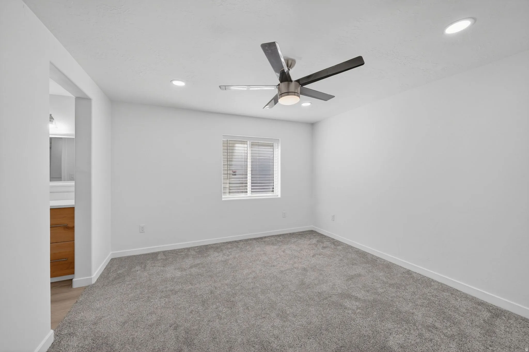 Carpeted room with a modern ceiling fan, recessed lighting, and a window with horizontal blinds