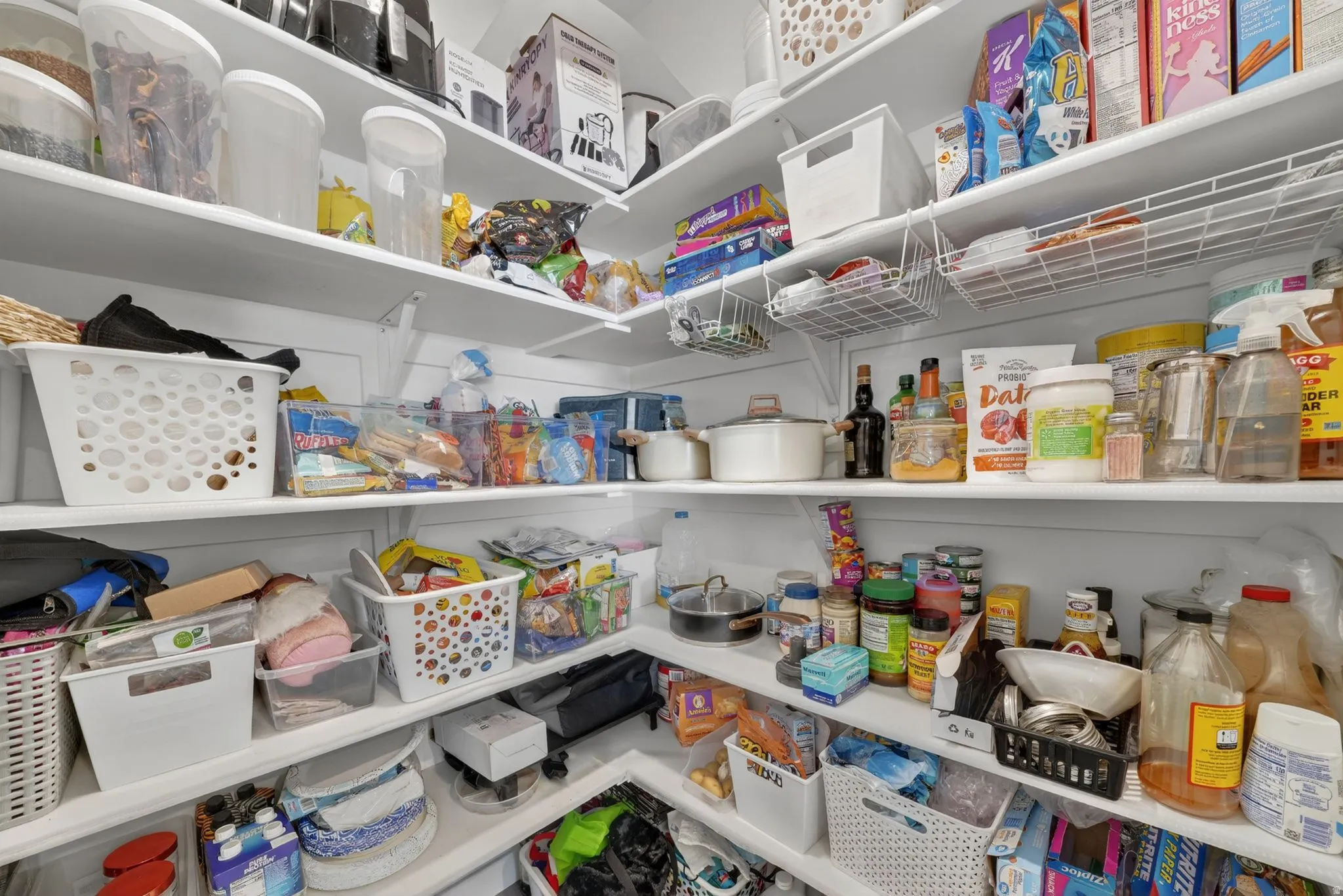 Corner pantry featuring multi-level shelving, integrated wire baskets, and white-painted wood finishes