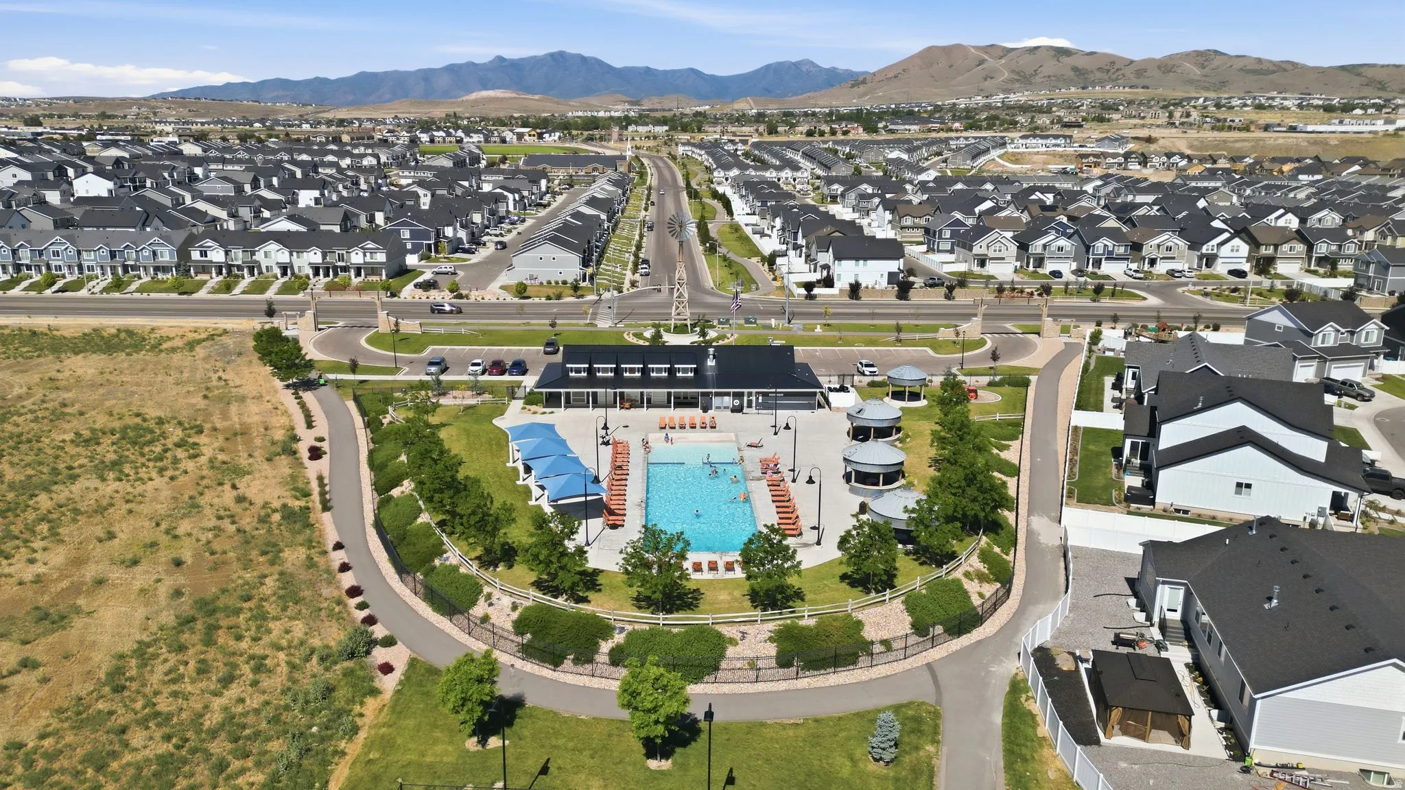 Community recreational area featuring an outdoor swimming pool, shaded seating areas, and a central clubhouse structure