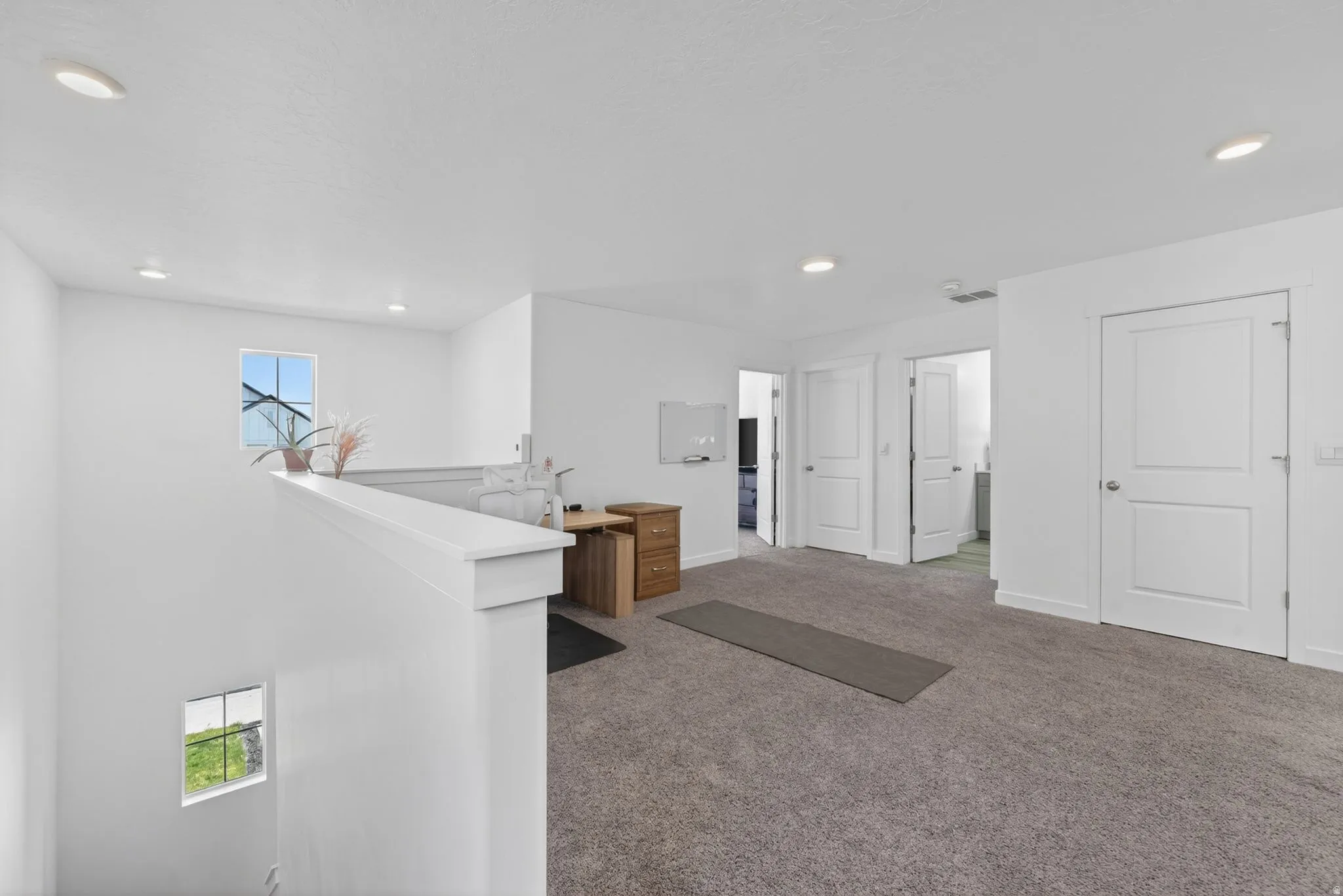 Spacious upper-level landing featuring neutral carpet, recessed lighting, and multiple paneled doors