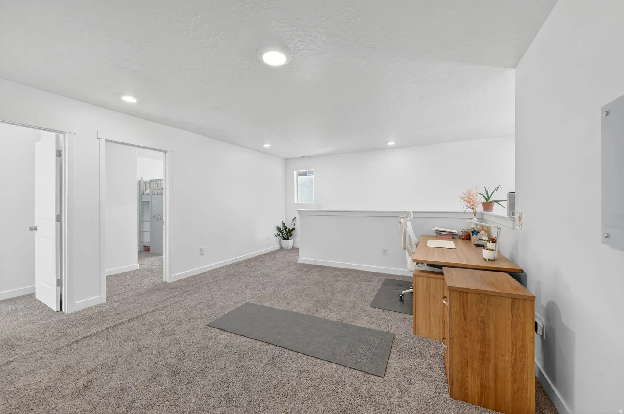 Carpeted loft area featuring recessed lighting, a window, and white walls