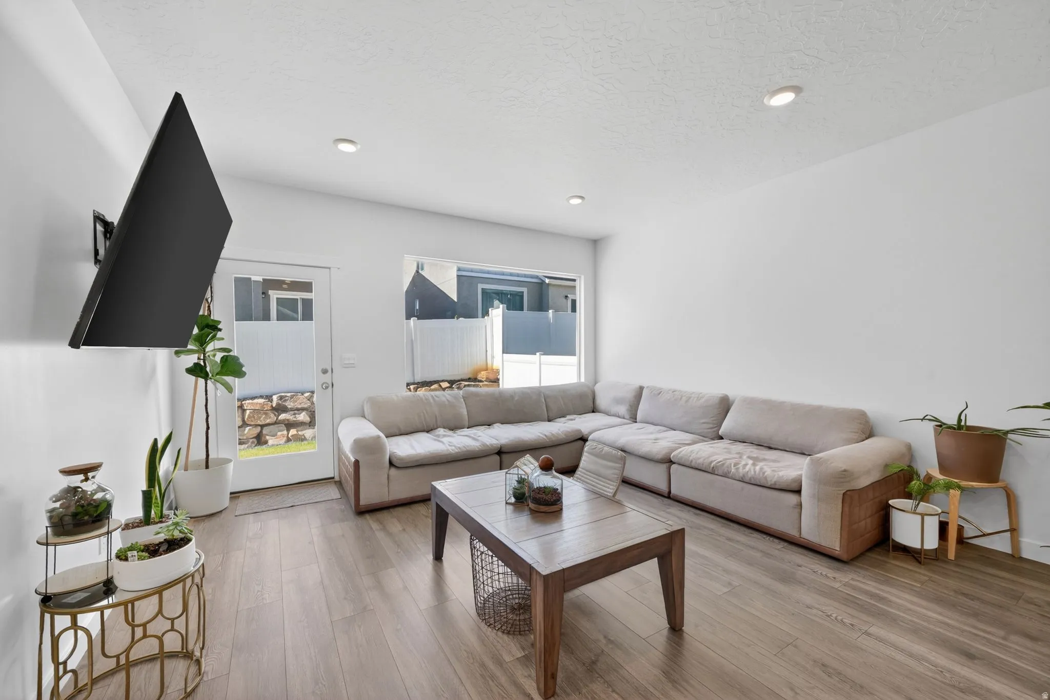 Open-concept living area featuring wood-finish flooring, recessed lighting, and a glass-paneled exterior door
