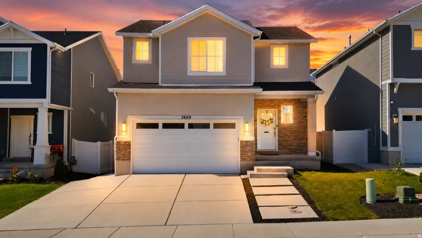Stucco and stone facade with a prominent front entrance, concrete driveway, and integrated two-car garage