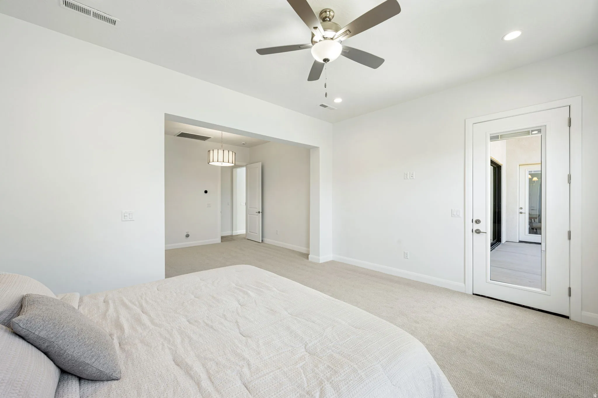Carpeted room with white walls, a ceiling fan with integrated lighting, and recessed ceiling lights