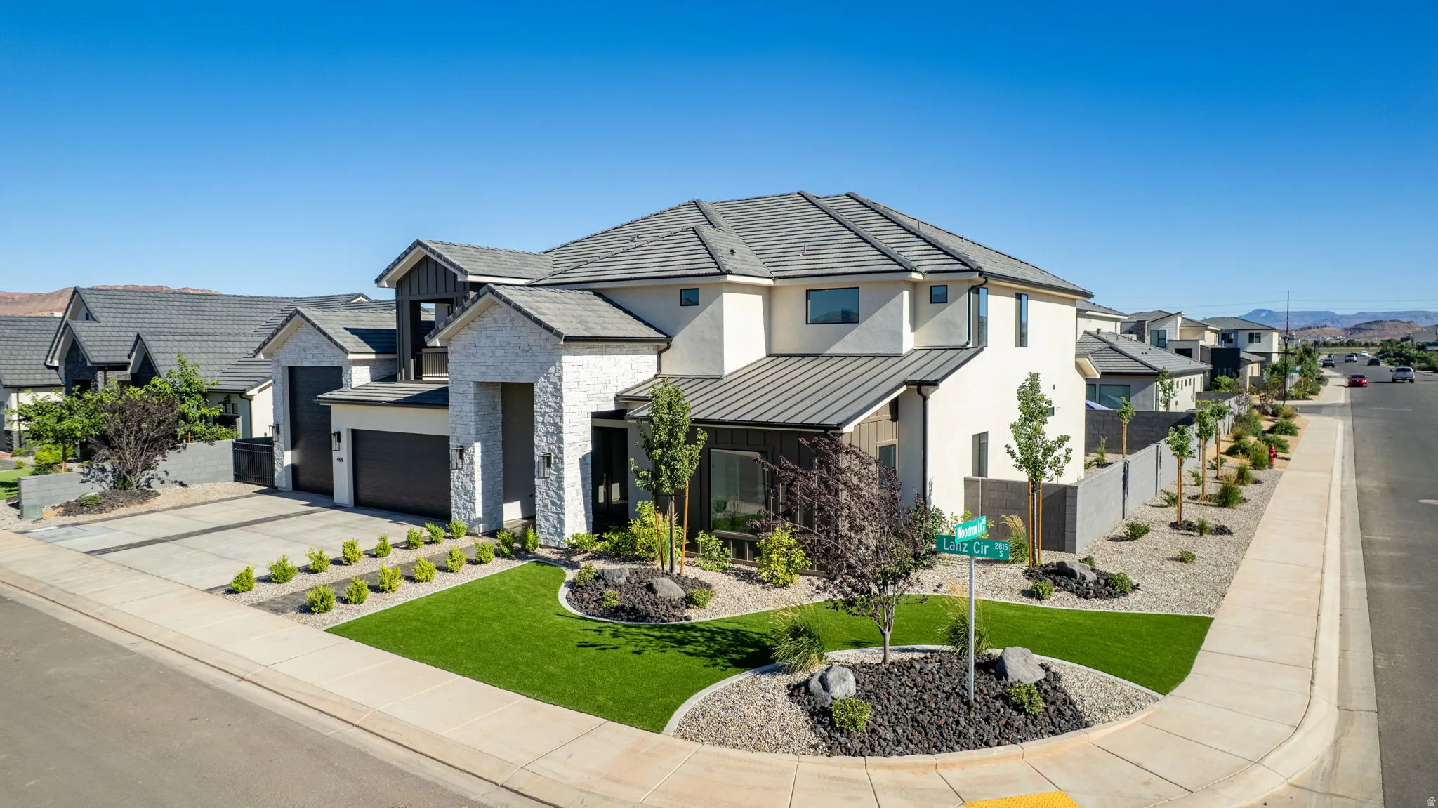 Contemporary two-story residence featuring a combination exterior of light-colored stucco and white stone veneer
