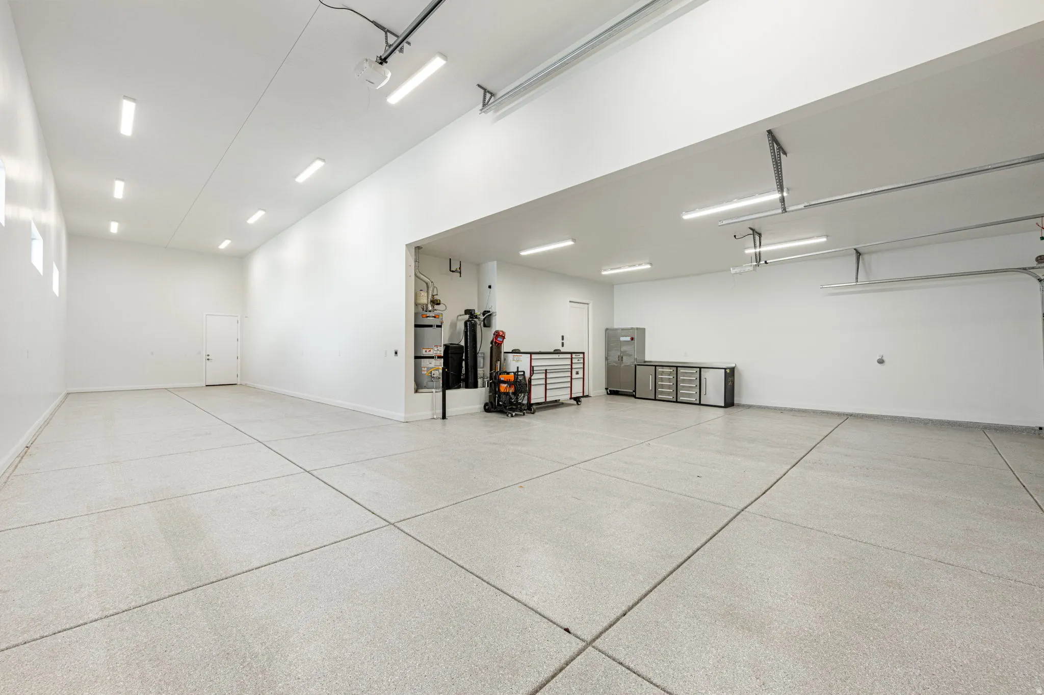 Spacious garage featuring a durable epoxy-coated concrete floor, bright overhead LED lighting, and a white interior paint scheme