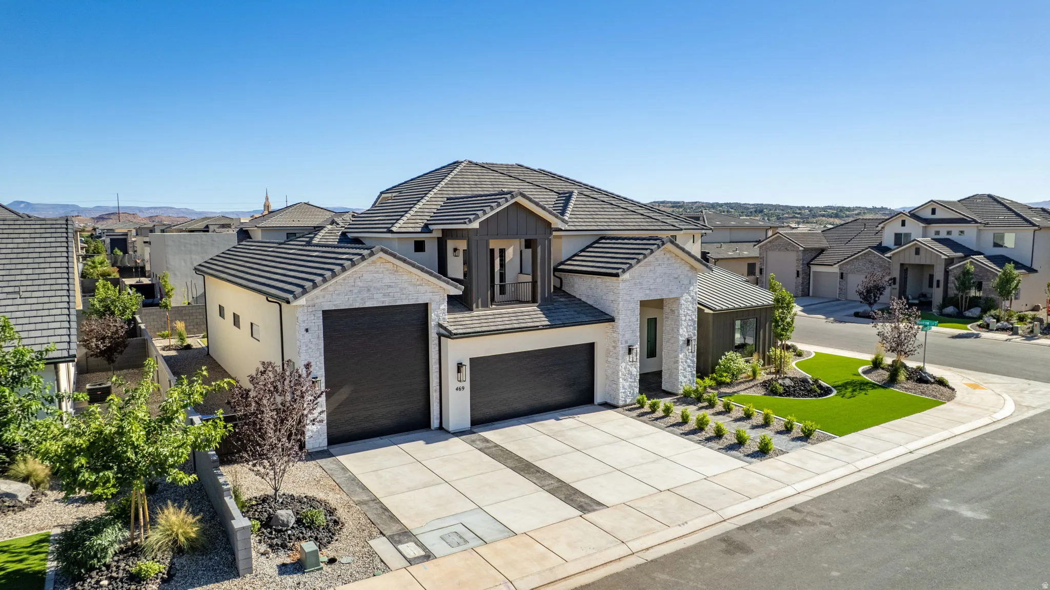Modern exterior featuring a prominent two-car garage, white stone facade accents, dark wood-look siding, and a multi-level roofline