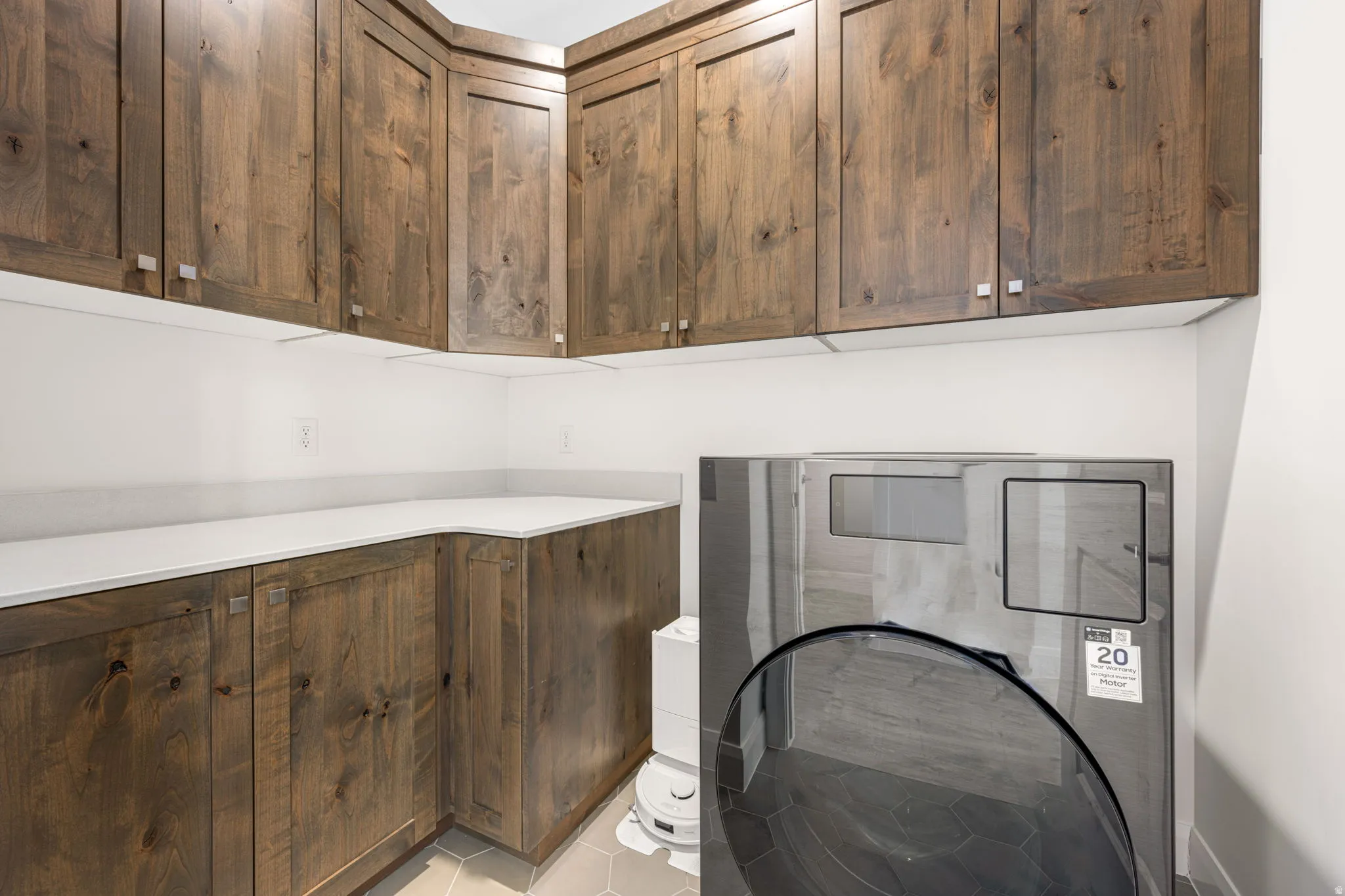 Laundry room featuring extensive wood cabinetry, white countertops, and hexagonal floor tiling