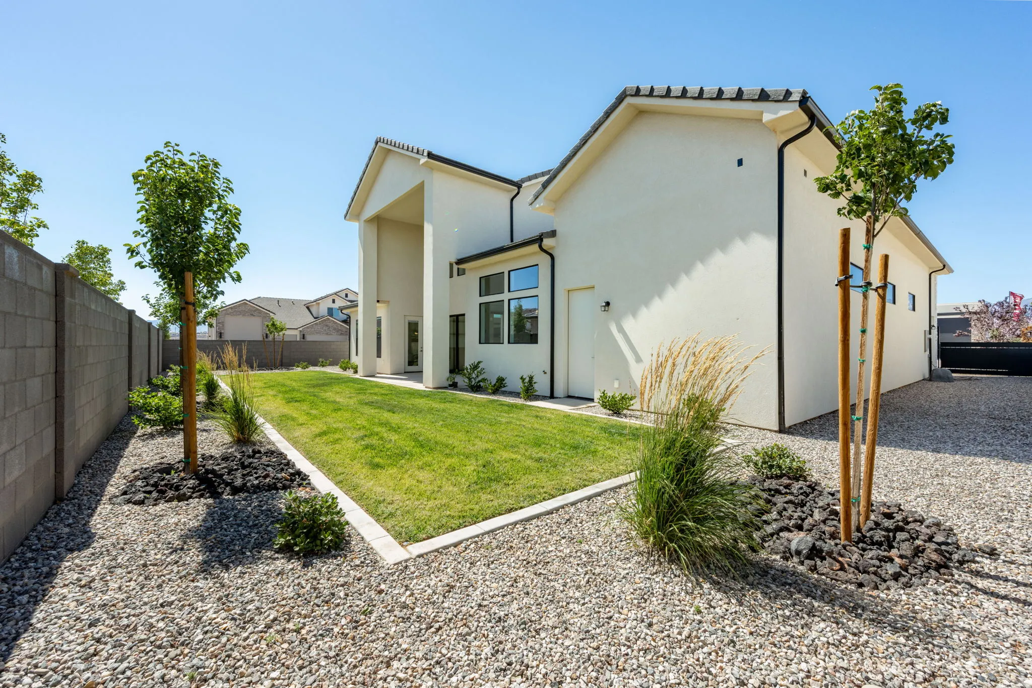 Spacious backyard featuring a rectangular lawn, gravel landscaping, and mature trees