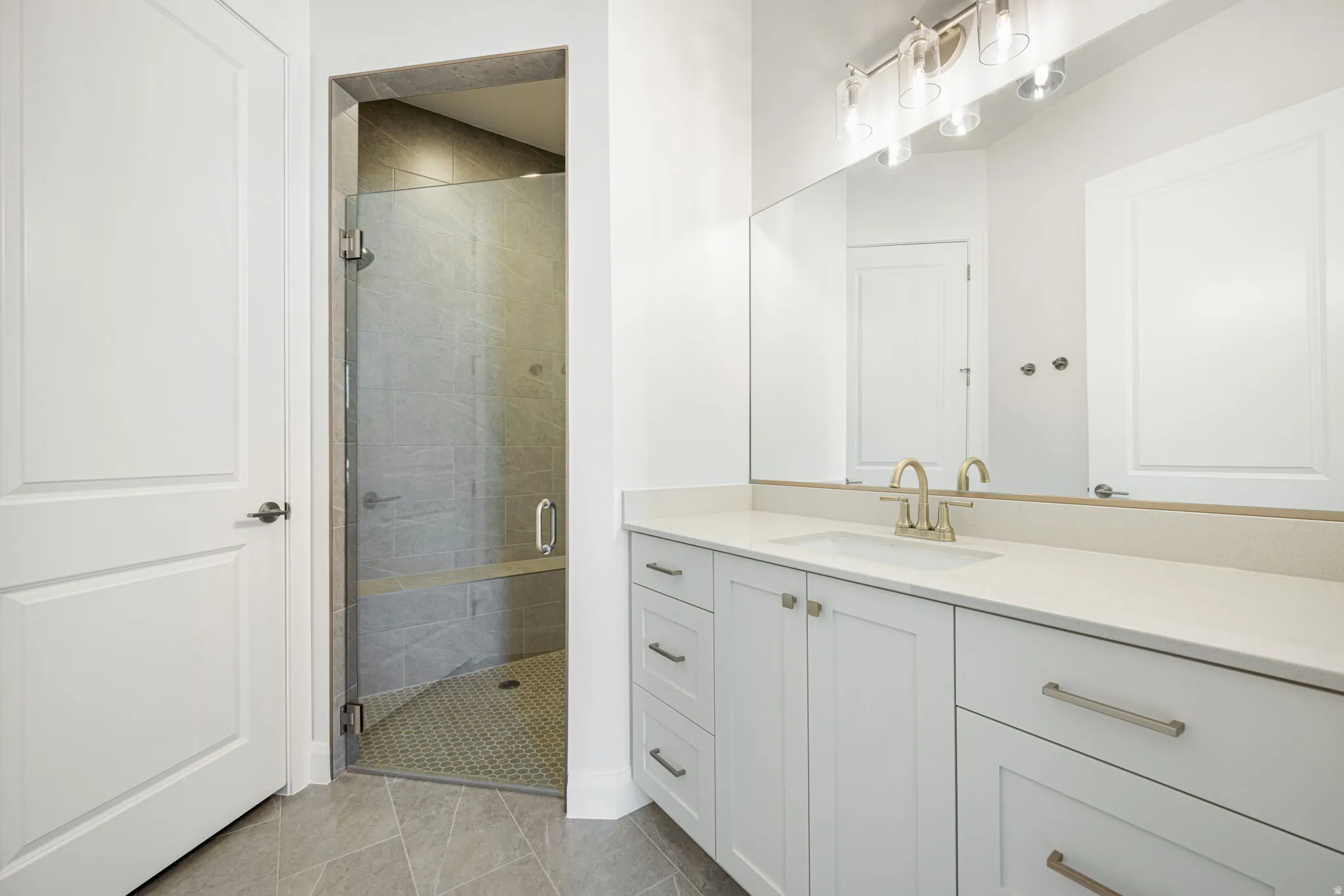 Contemporary bathroom featuring a spacious vanity with an undermount sink, a large wall mirror, and a glass-enclosed shower with a built-in bench