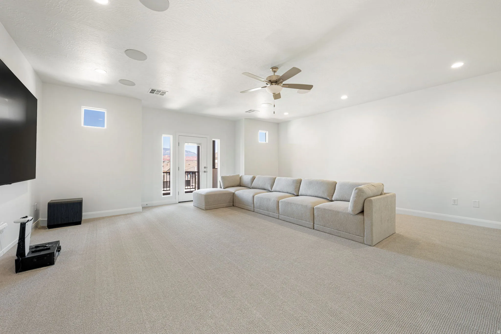 Spacious room featuring light-toned carpeting, recessed ceiling lighting, and a ceiling fan