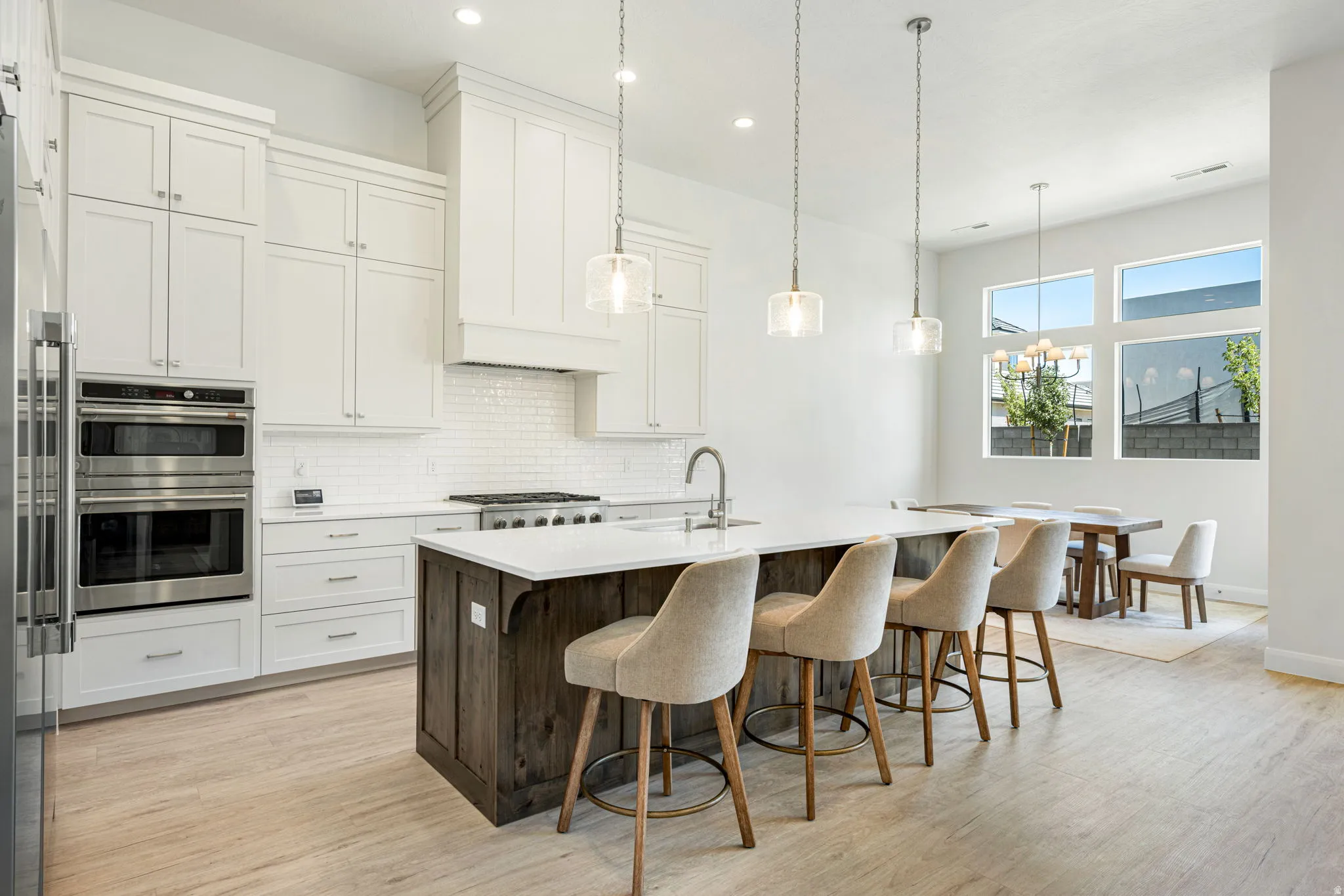 Contemporary kitchen featuring a large center island with a wood-finish base, white countertop, and three pendant lights
