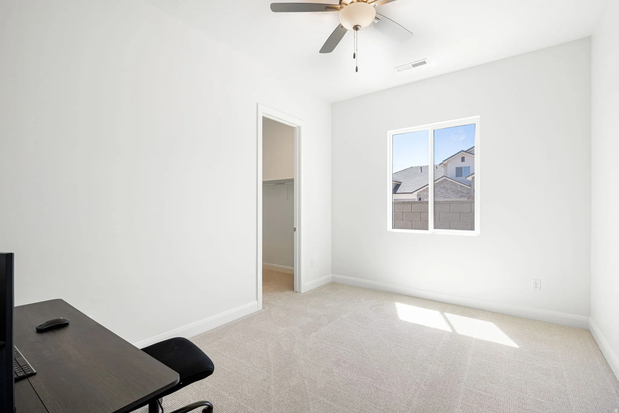 Spacious interior room featuring light-colored carpeting, white baseboards, and a contemporary ceiling fan