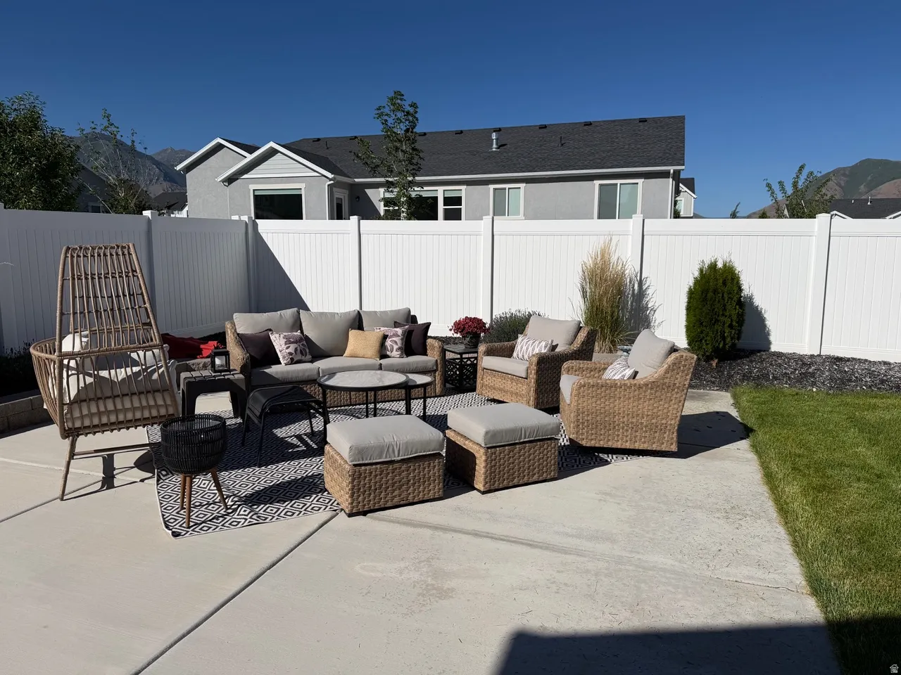 Concrete patio featuring a white privacy fence and a manicured lawn