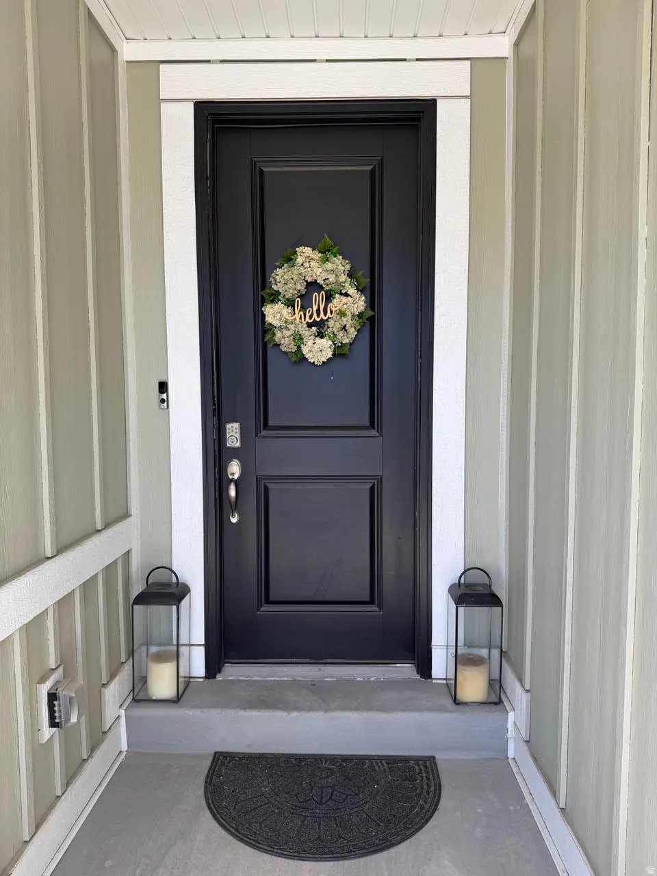 Front entry featuring a paneled door with polished hardware, contrasting trim, and vertical siding