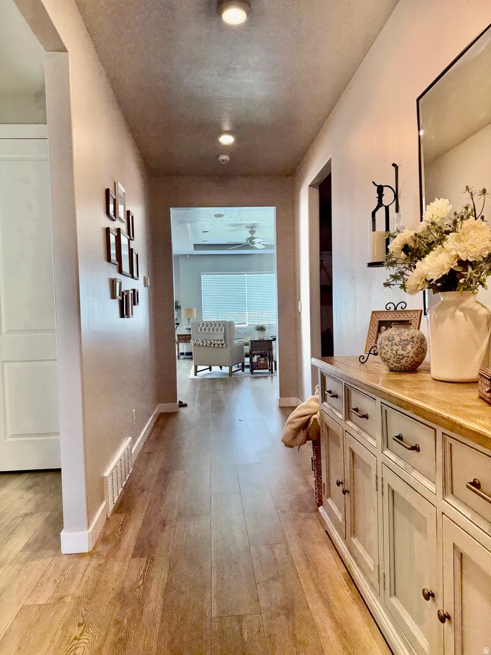 Hallway with wood-finish flooring, recessed lighting, and a console cabinet with multiple drawers and cabinet storage