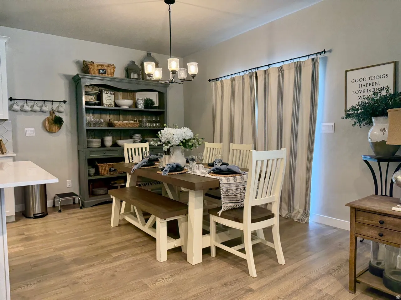 Open-concept dining area featuring wood-finish flooring, a contemporary chandelier, and a built-in display hutch