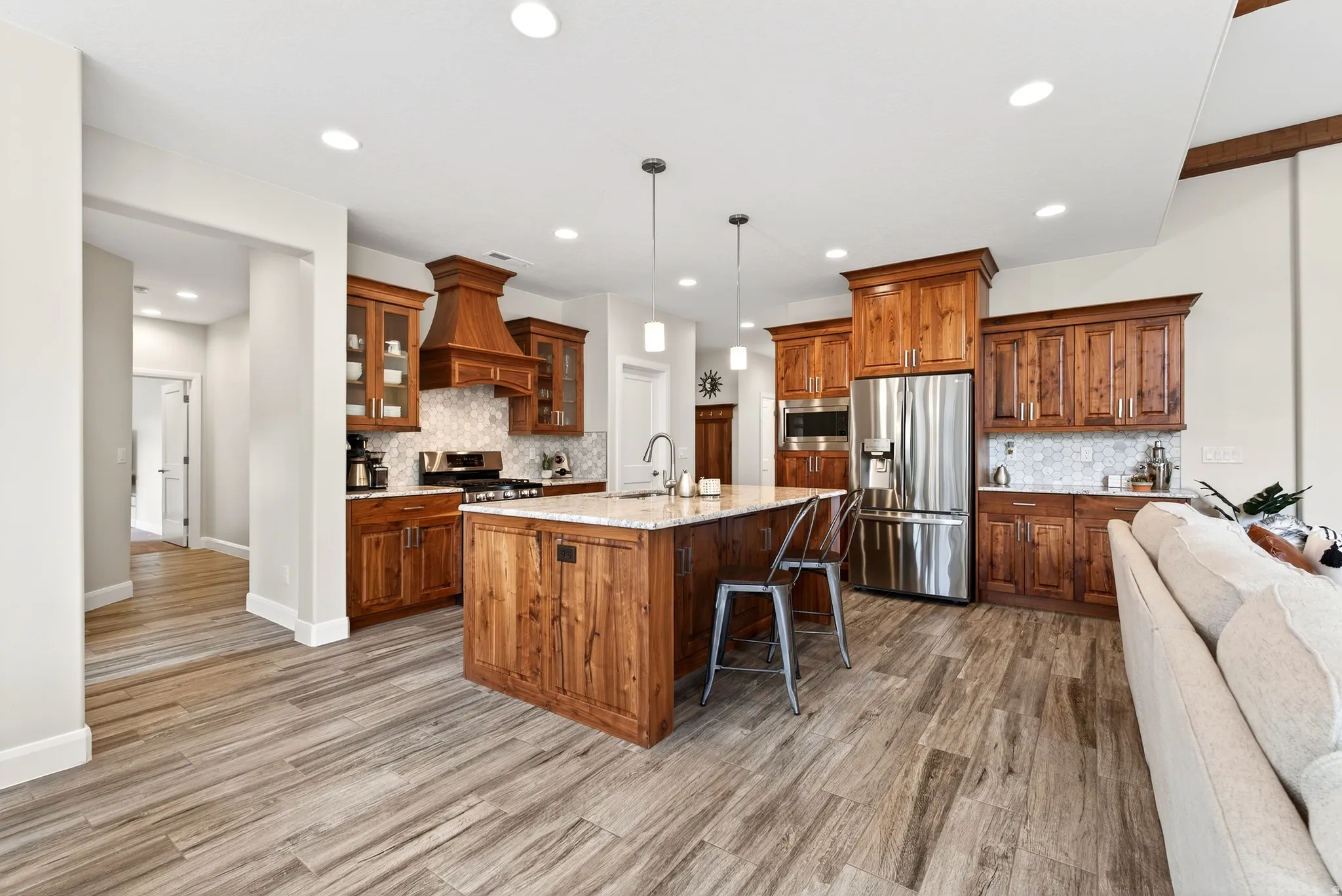 Expansive kitchen featuring wood cabinetry, stainless steel appliances, a center island with countertop seating, and wood-finish flooring