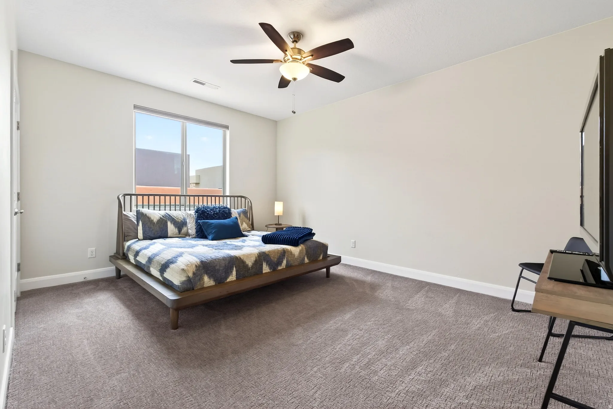 Neutral tone walls with a picture window, complemented by a ceiling fan with integrated lighting