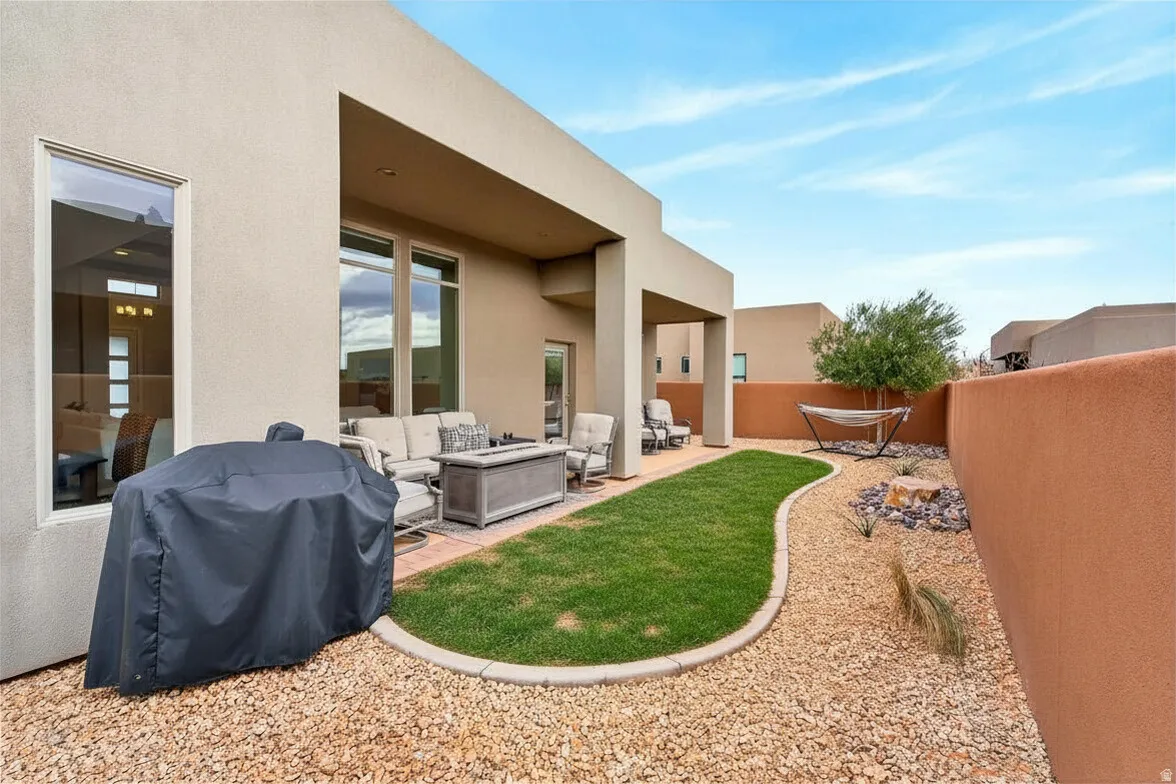 Enclosed backyard with a covered patio, stucco exterior, gravel landscaping, a curved grass area, and a privacy wall