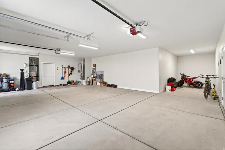 Spacious garage with light grey concrete flooring, white painted walls, and overhead fluorescent lighting