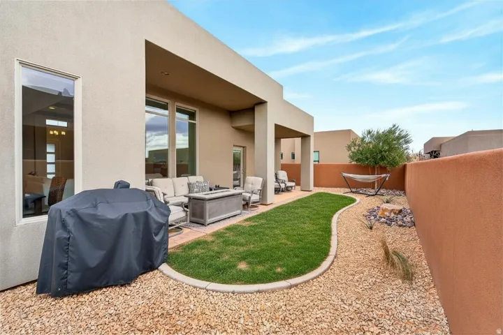 Enclosed backyard with a covered patio, stucco exterior, gravel landscaping, a curved grass area, and a privacy wall