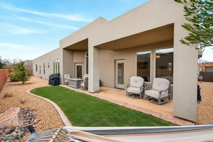 Grass AI enhanced to show.Rear exterior featuring a covered patio with recessed lighting, stucco finish, and multiple windows