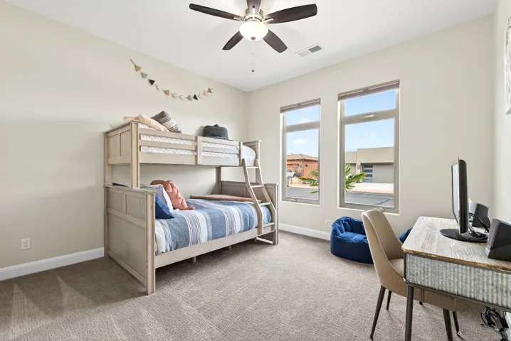Bedroom featuring light-toned carpeting, neutral wall paint, and a ceiling fan with integrated lighting