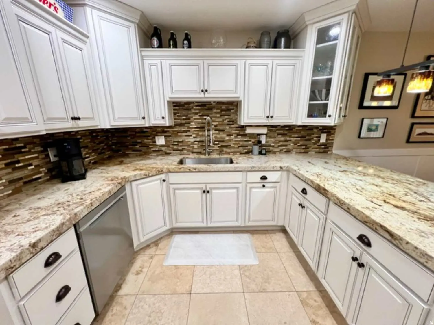 U-shaped kitchen featuring white cabinetry, stone countertops, a mosaic tile backsplash, stainless steel sink with a gooseneck faucet, and light-toned tile flooring