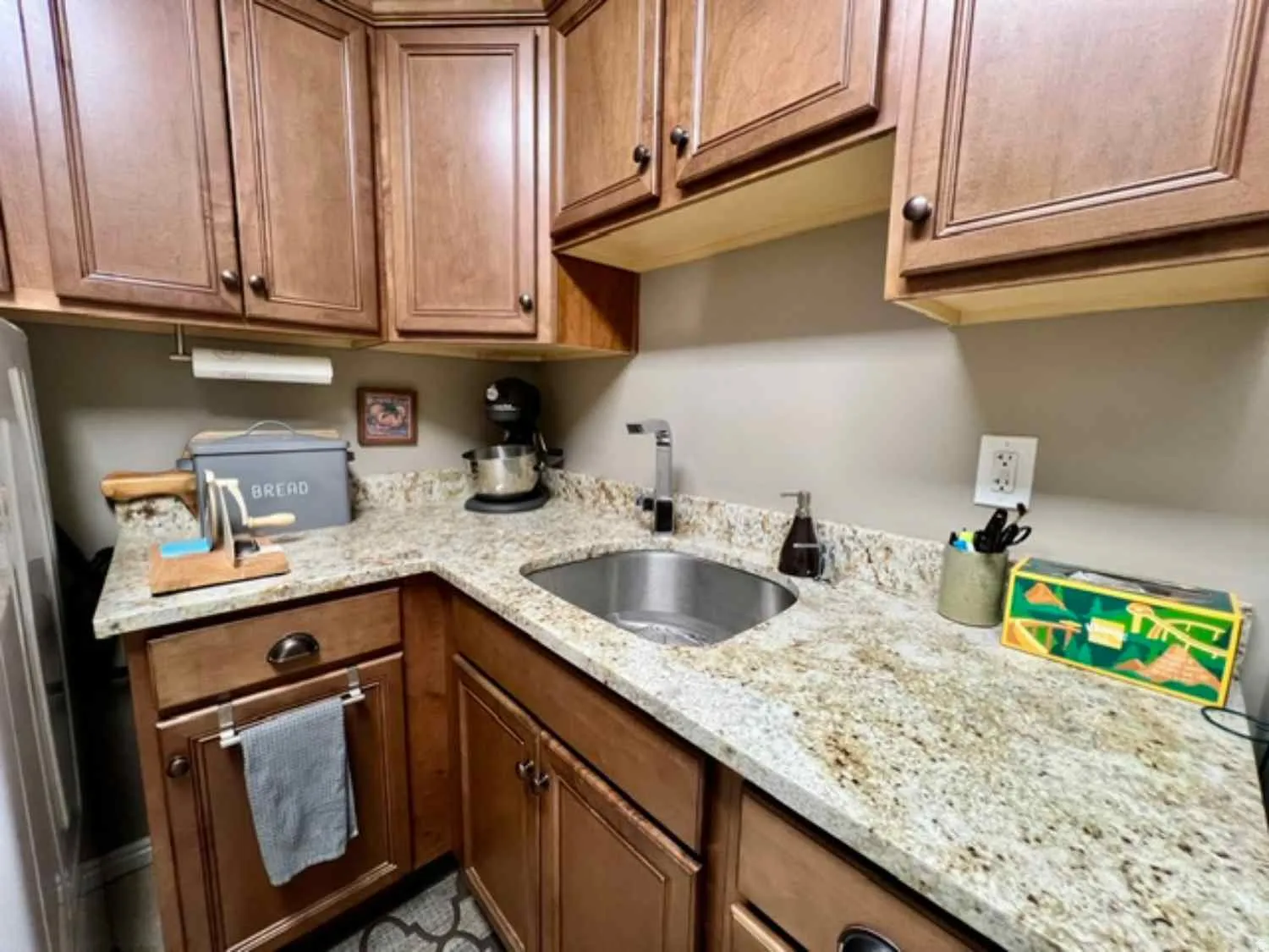 Kitchenette featuring wood cabinetry, speckled countertop, an undermount stainless steel sink, and a chrome faucet