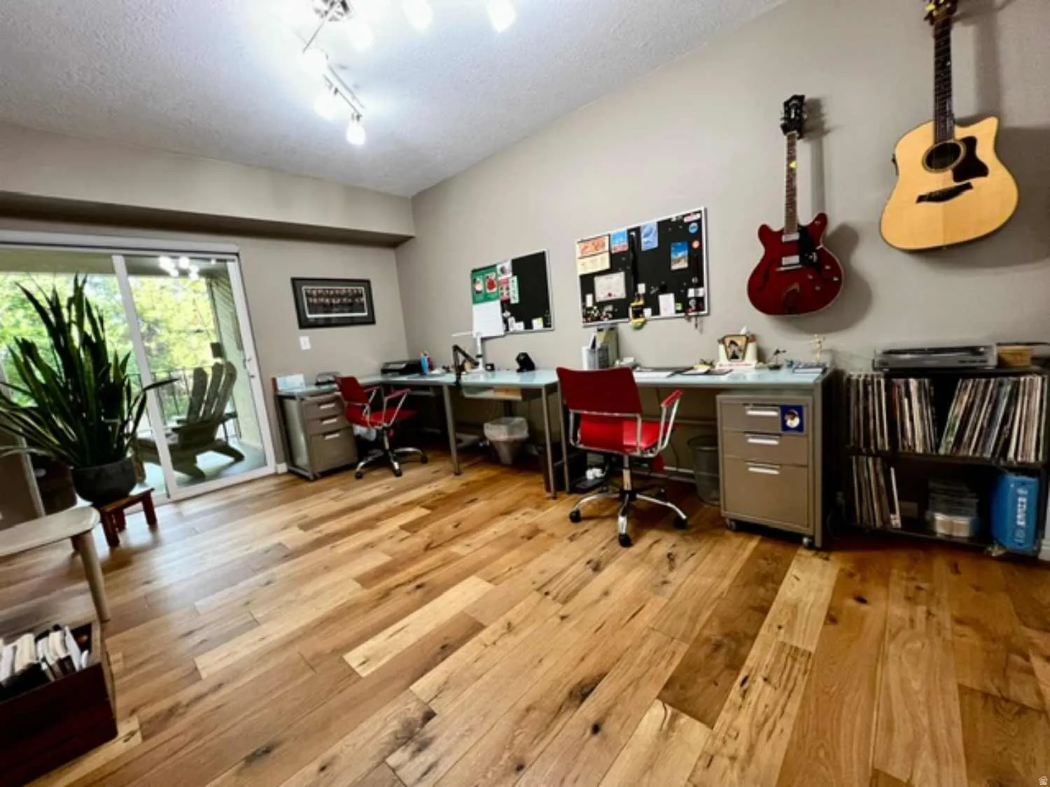 Spacious room featuring wood-finish flooring and a contemporary track lighting fixture