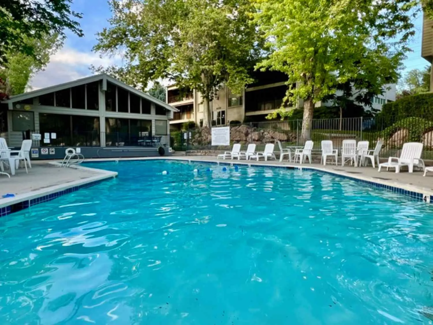 Outdoor swimming pool featuring a tiled edge, surrounded by a concrete deck with lounge seating