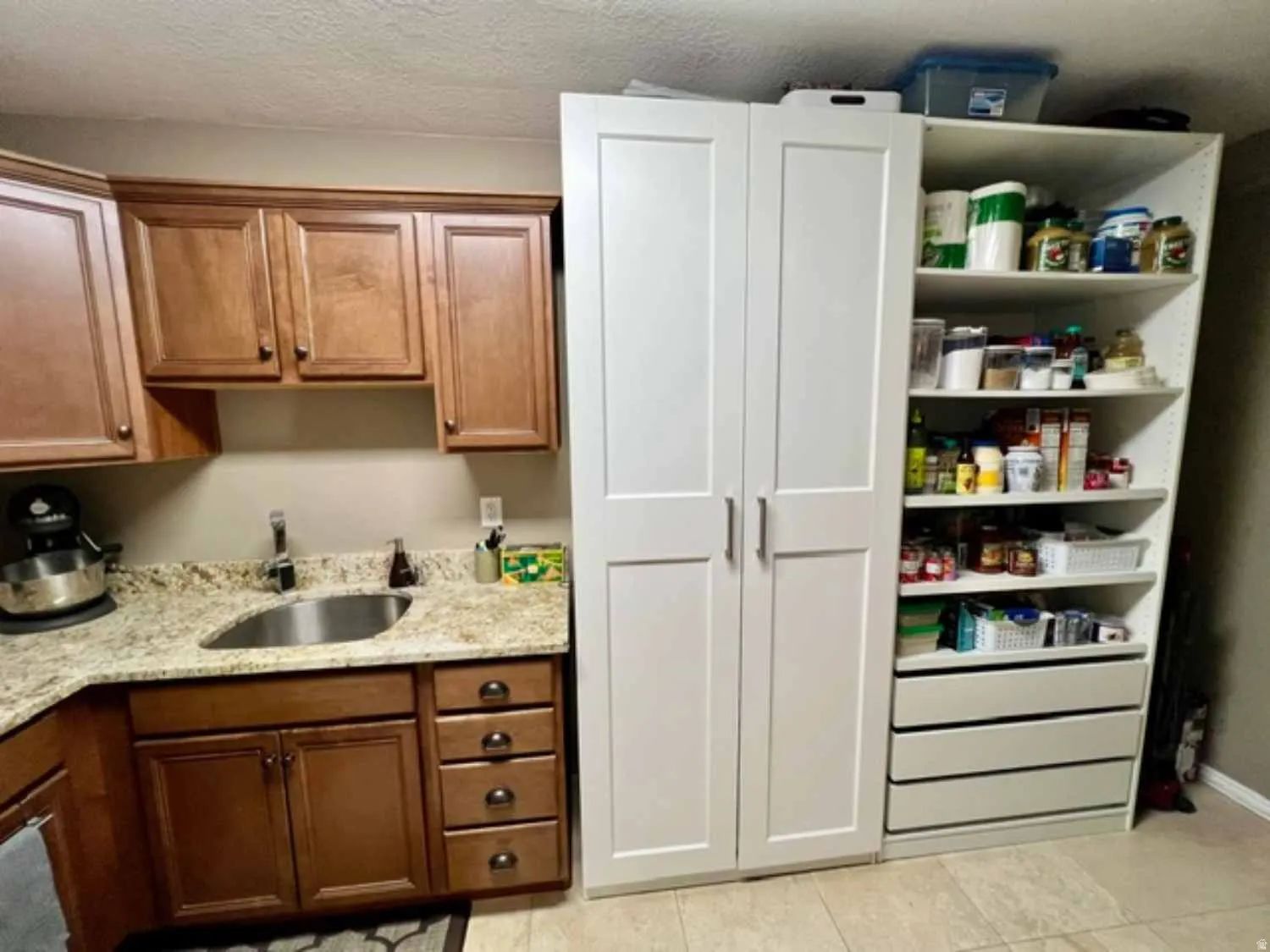 Kitchen area featuring a stainless steel undermount sink, granite-style countertops, and wood cabinetry