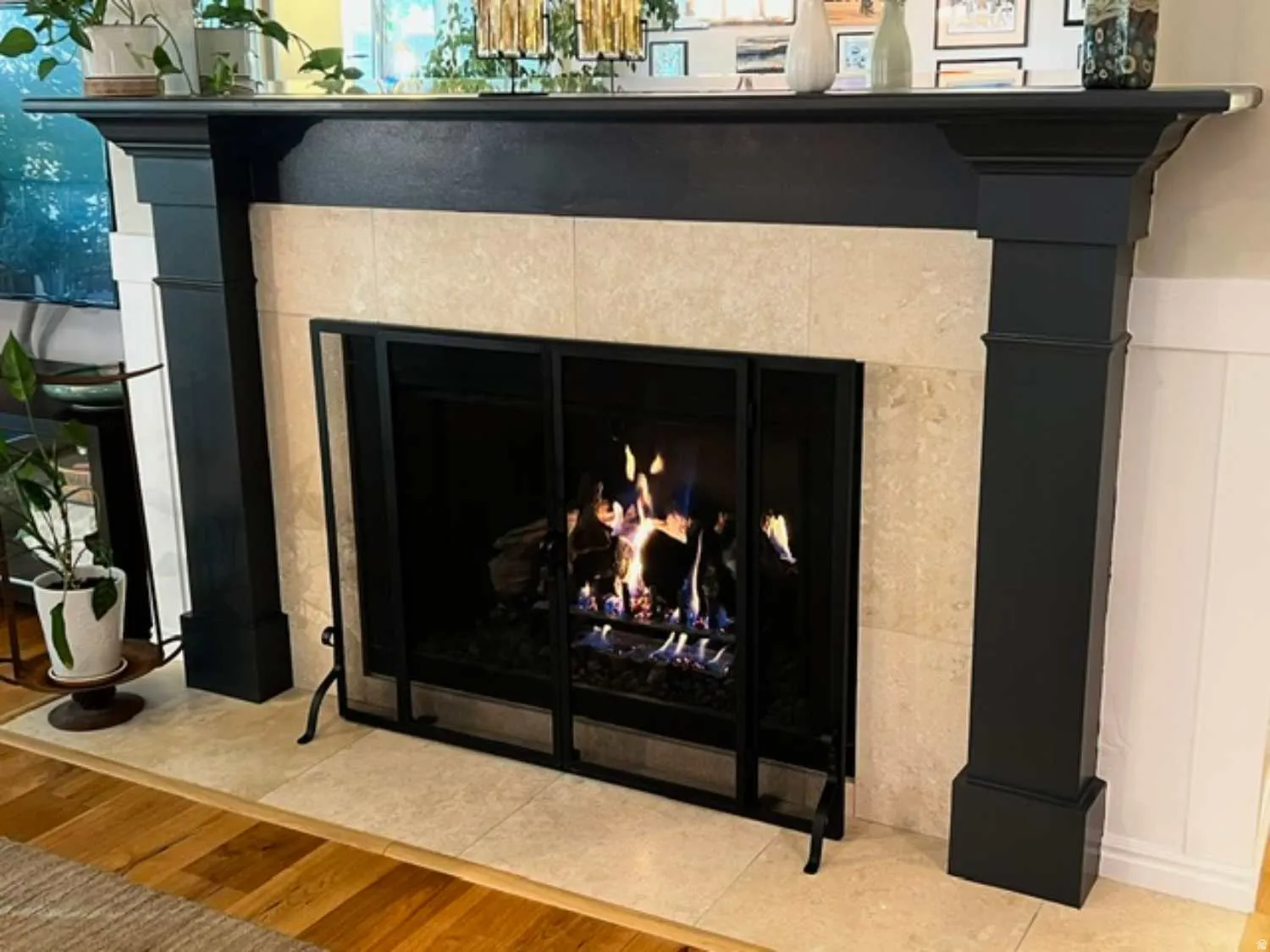 Fireplace featuring a substantial dark-toned wood mantelpiece with decorative corbels, a tiled surround, a built-in firebox with an integrated screen, and a tiled hearth