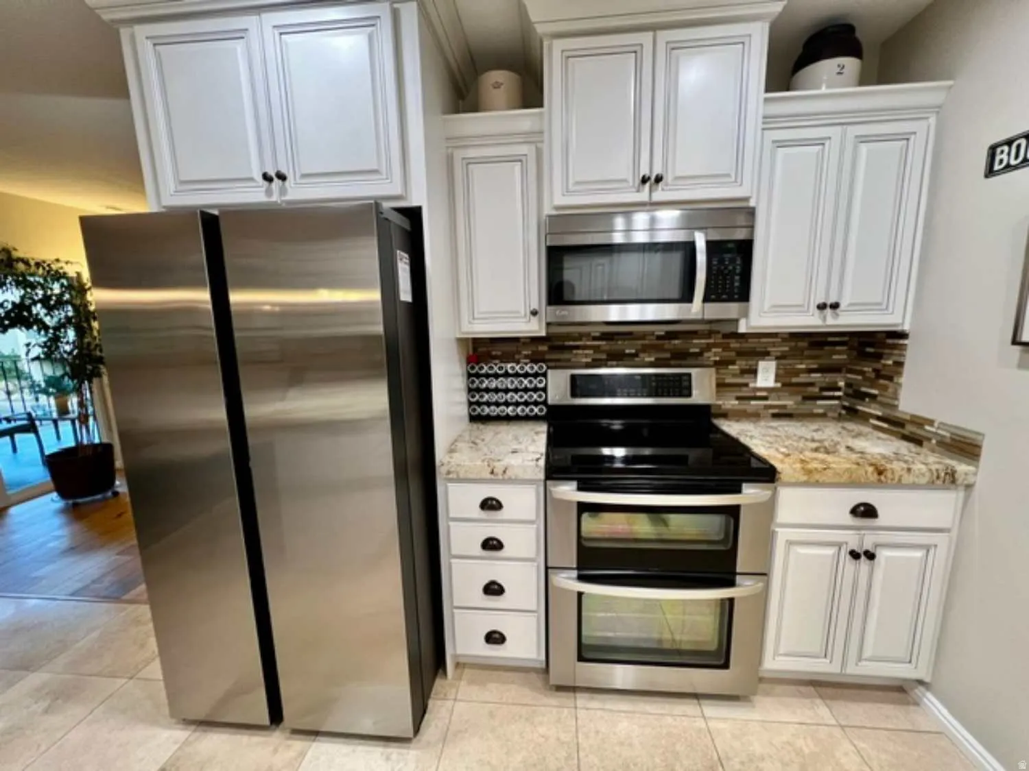 Modern kitchen featuring white cabinetry with dark hardware, stainless steel appliances, a double oven range, and a mosaic tile backsplash
