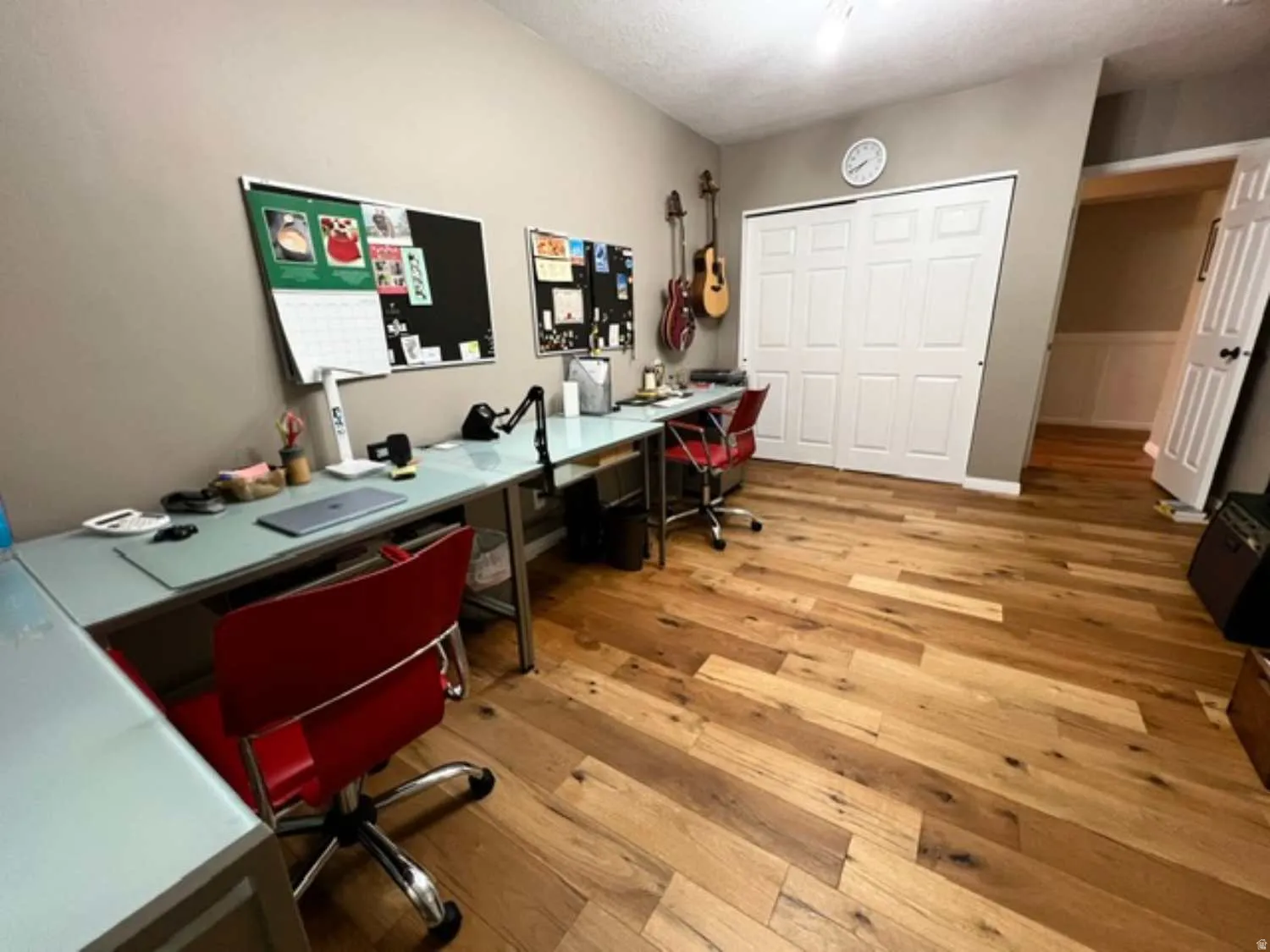 Hardwood-style flooring throughout this room, featuring a white bi-fold closet door, neutral wall paint, and white trim