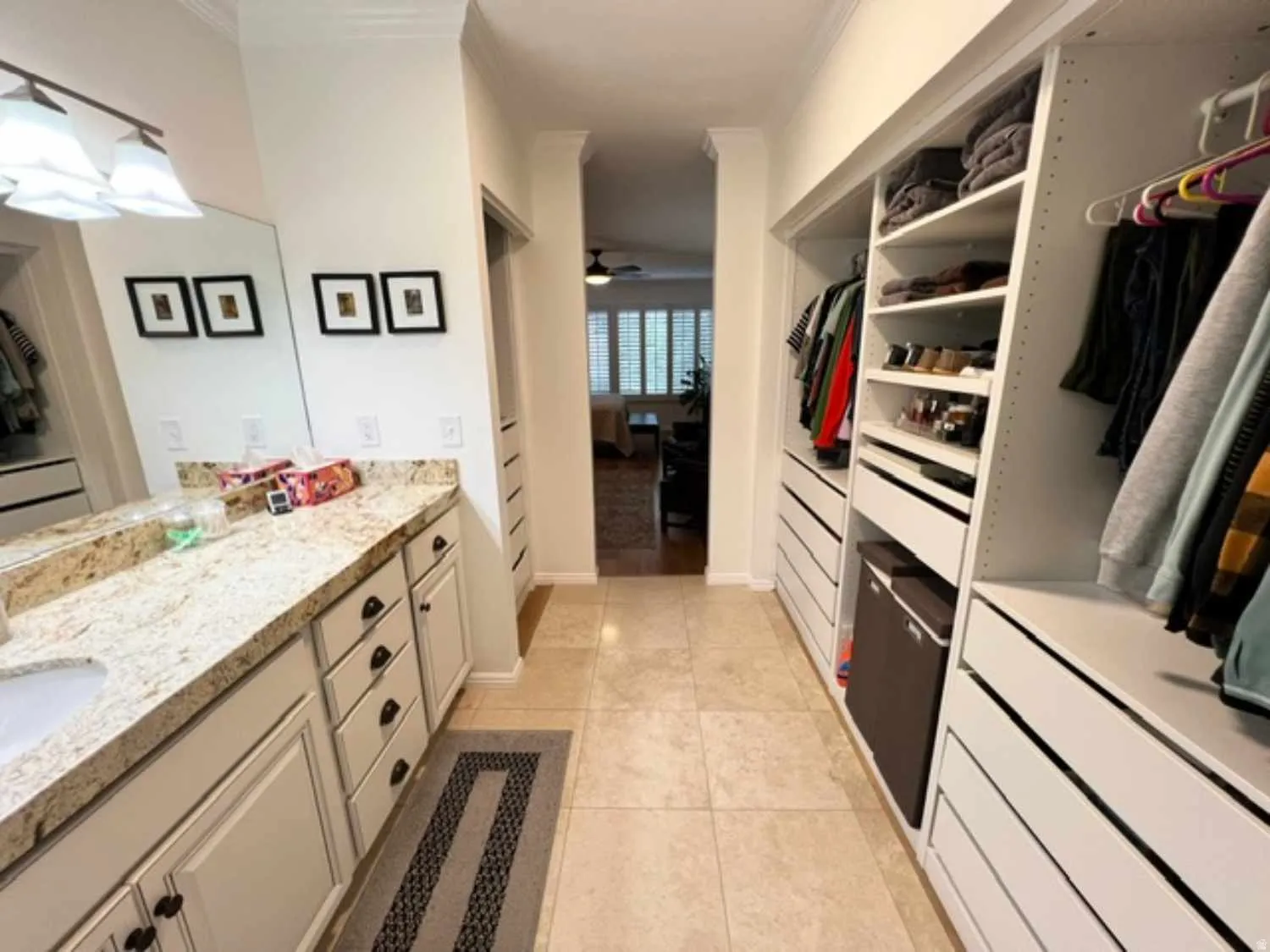Walk-through dressing area featuring custom built-in cabinetry, extensive storage, and a vanity with granite-finish countertops