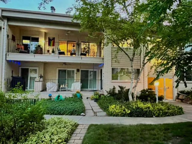 Multi-story exterior with two levels of private balconies and patios, featuring sliding glass doors, wrought iron railings, and mature landscaping