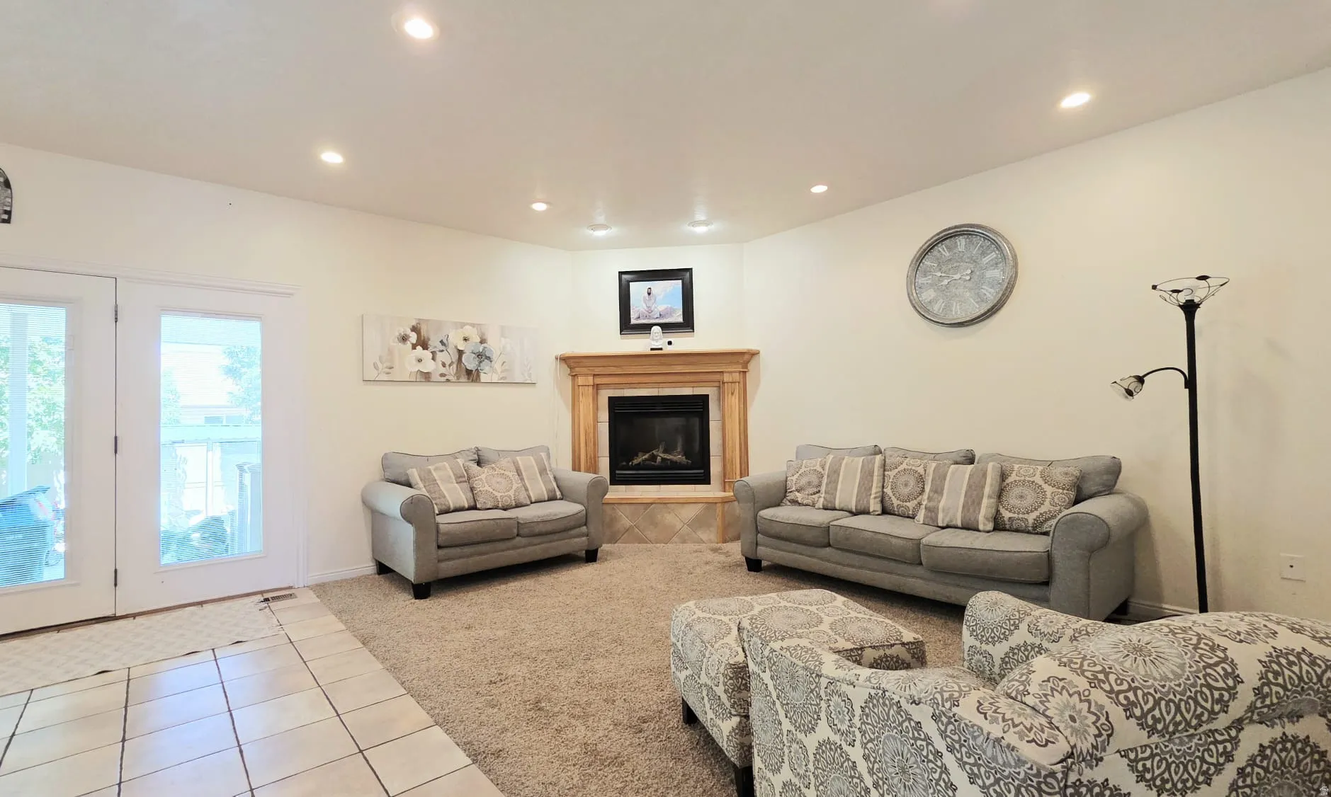 Living area with a corner fireplace featuring a natural wood mantel and tile surround
