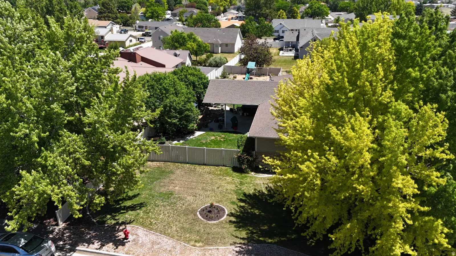 Expansive backyard featuring a manicured lawn, established trees, and a white privacy fence