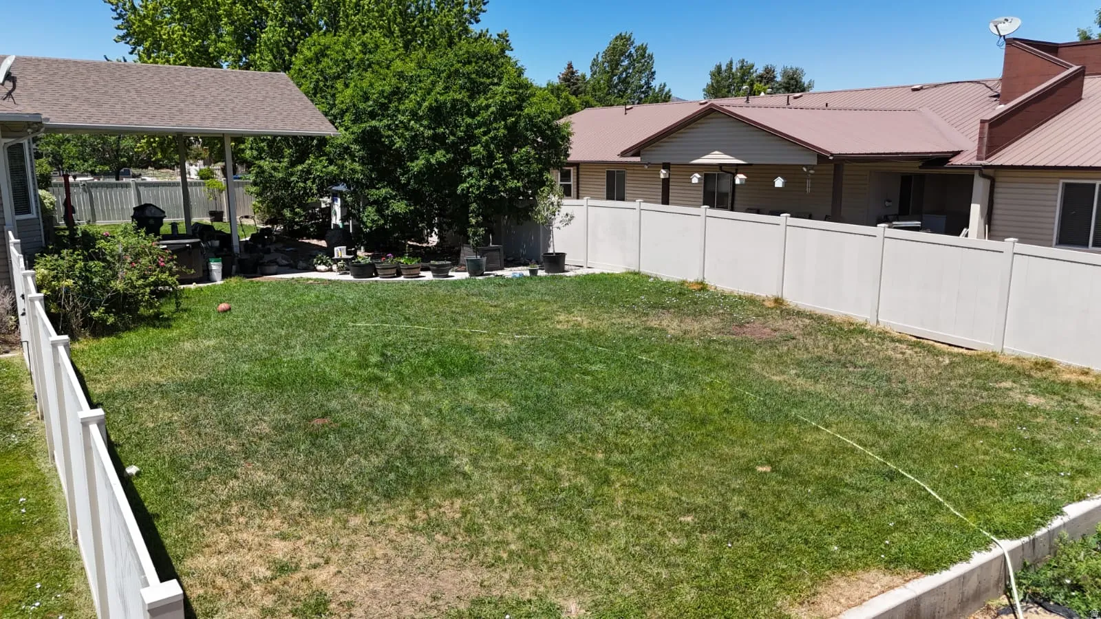 Expansive green lawn area bordered by a white vinyl fence