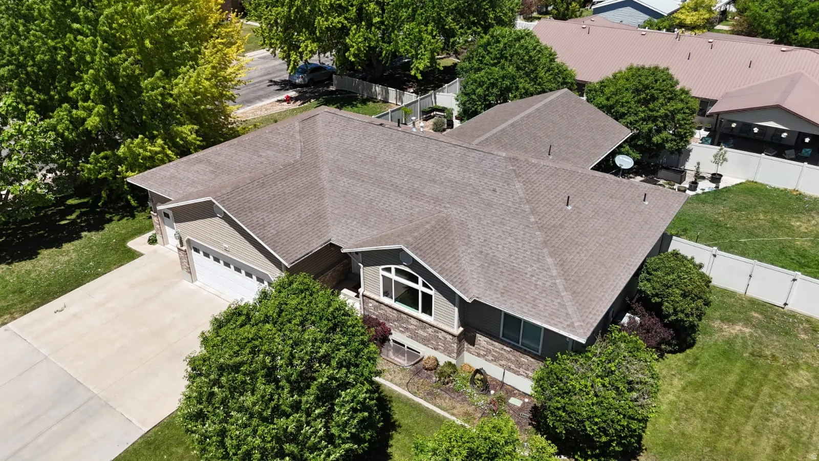 Single-story residence featuring a brown shingle roof, light-colored siding, and stone facade accents
