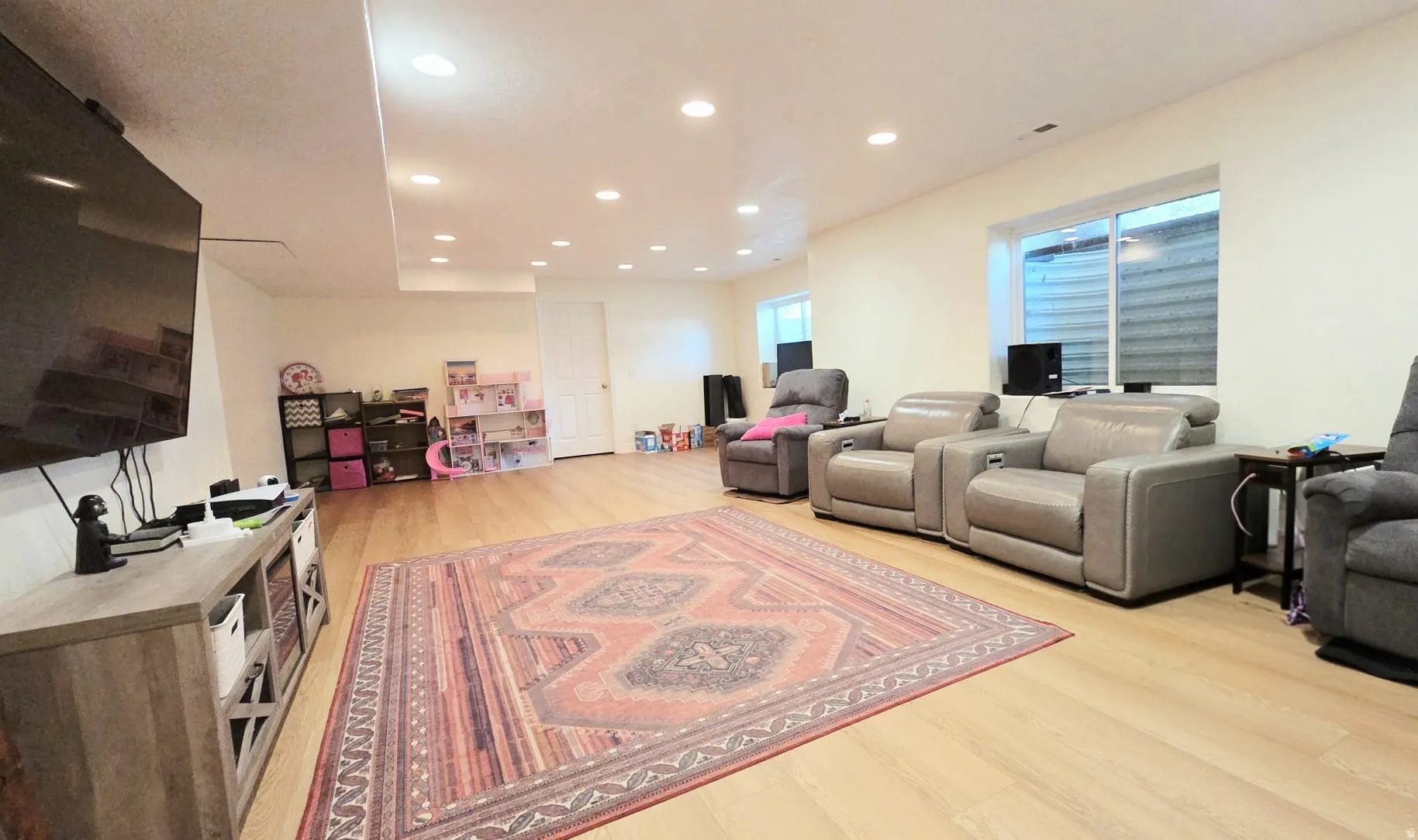 Spacious living area featuring wood-finish flooring, recessed lighting, and a window well for natural light