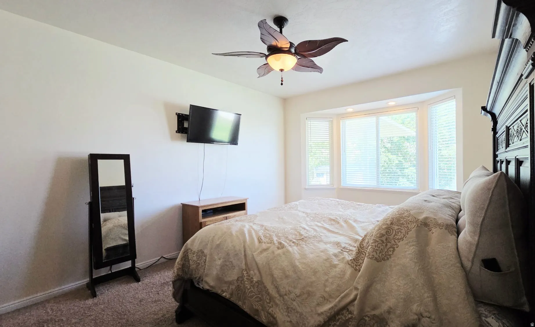 Bright interior space featuring a bay window with blinds, ceiling fan with integrated lighting, and neutral wall paint