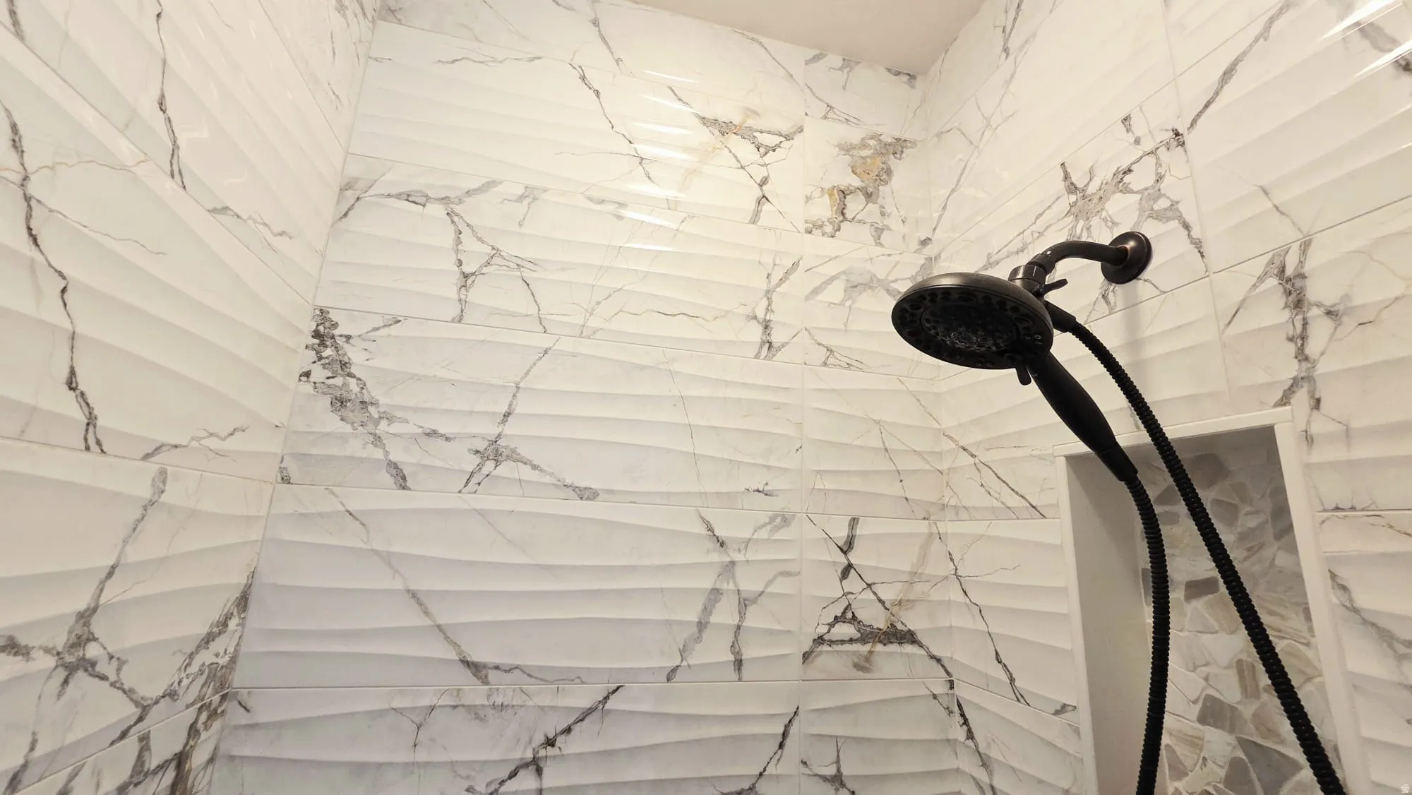 Shower stall featuring textured and veined wall tiles