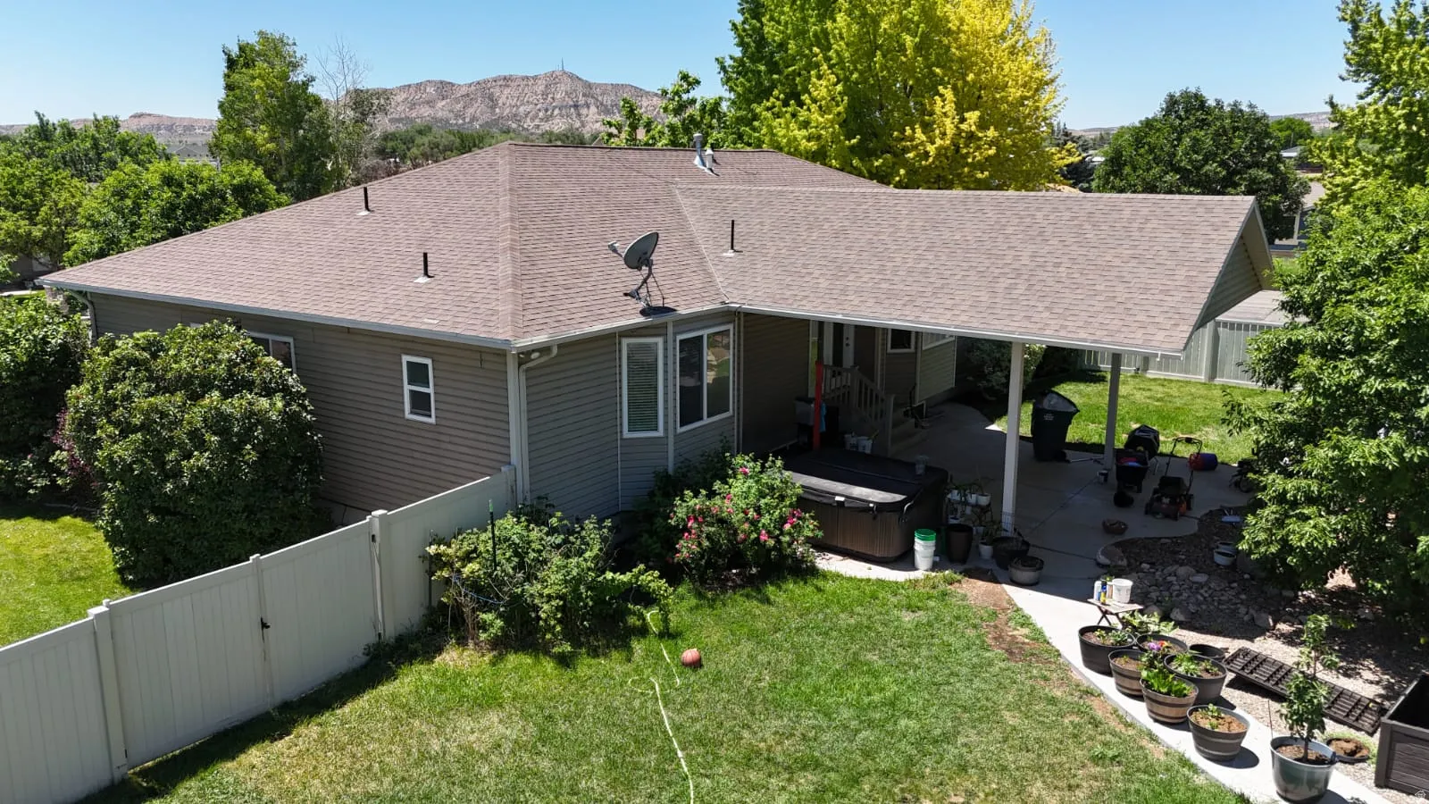 Expansive backyard featuring a covered patio, a privacy fence, and mature landscaping
