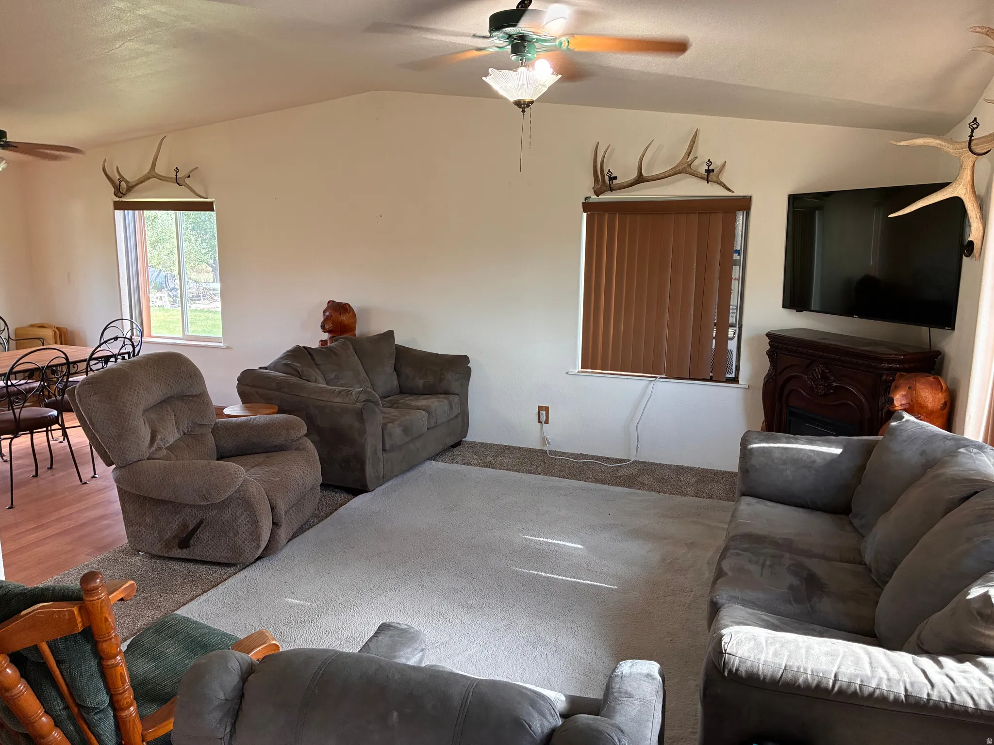 Living area featuring a vaulted ceiling with a ceiling fan, and windows with outdoor views.